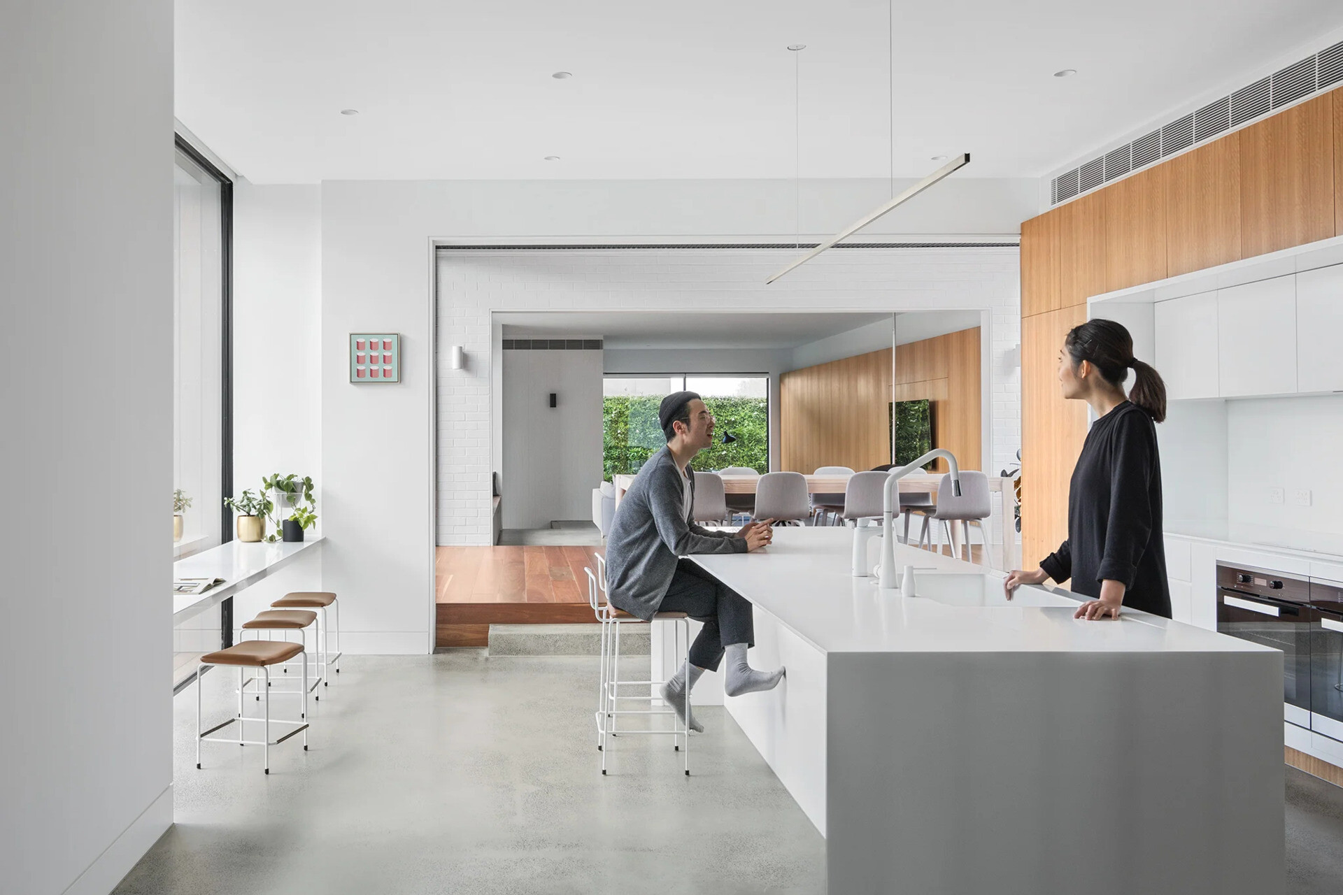 A modern kitchen with a white island, window-side seating, and hidden appliances blends function and style effortlessly.