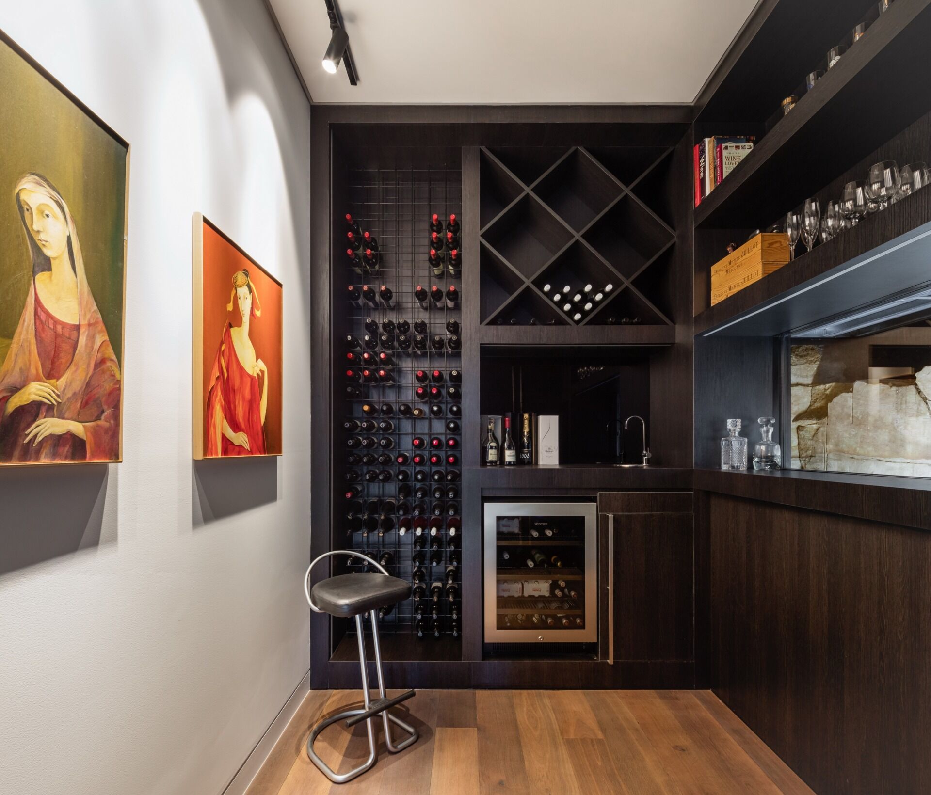 Dark joinery transforms the wine cellar into a moody, functional storage space.