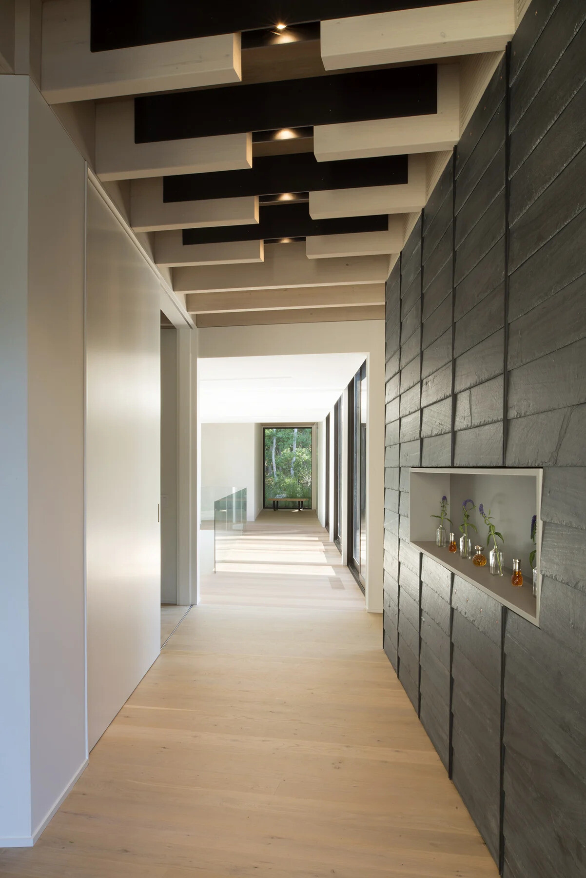 The hallway reveals close up views of the steel flitch plates that connect the home’s exposed timber beams.