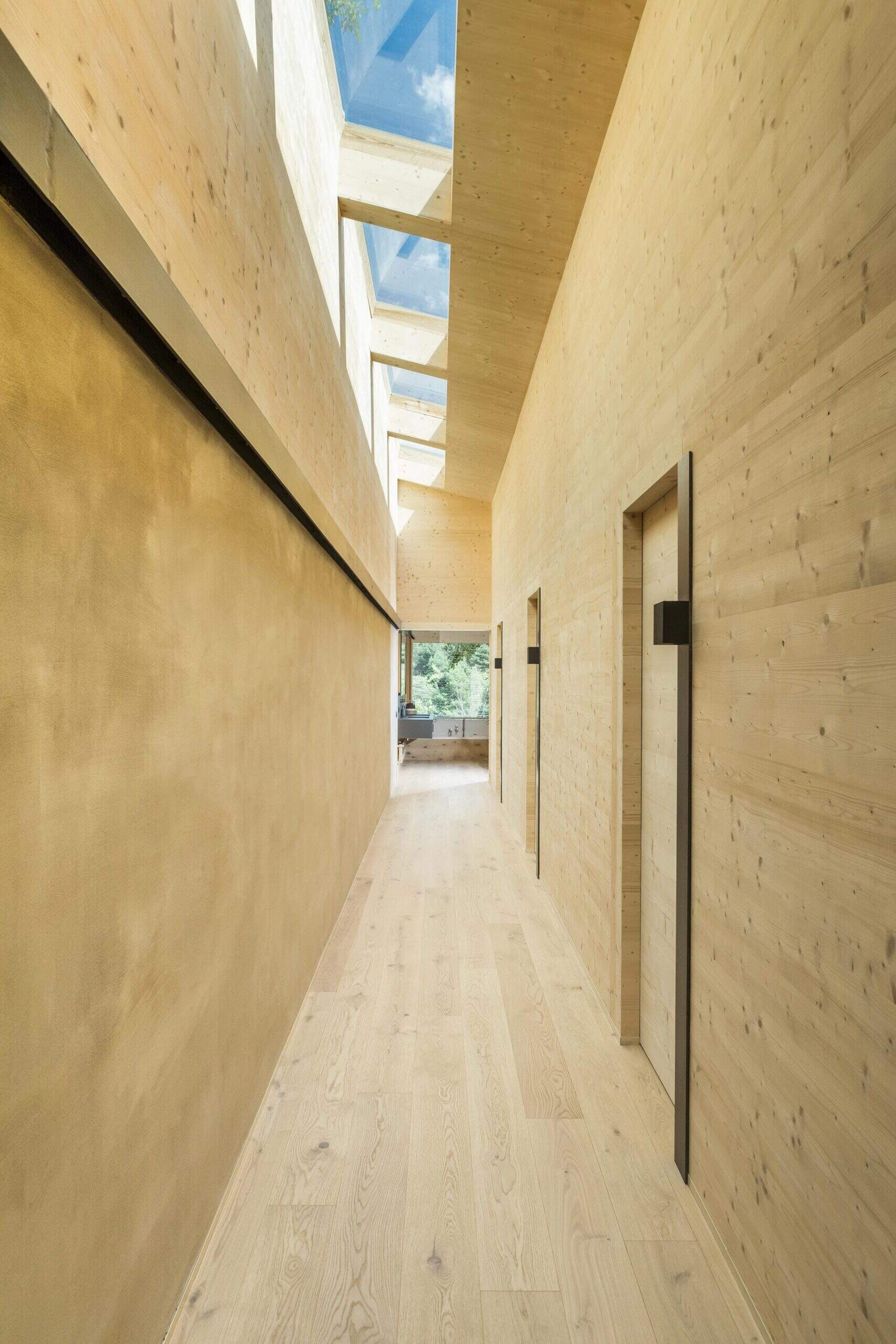 A skylit hallway tucked beneath the stairs leads quietly to the home’s private spaces.