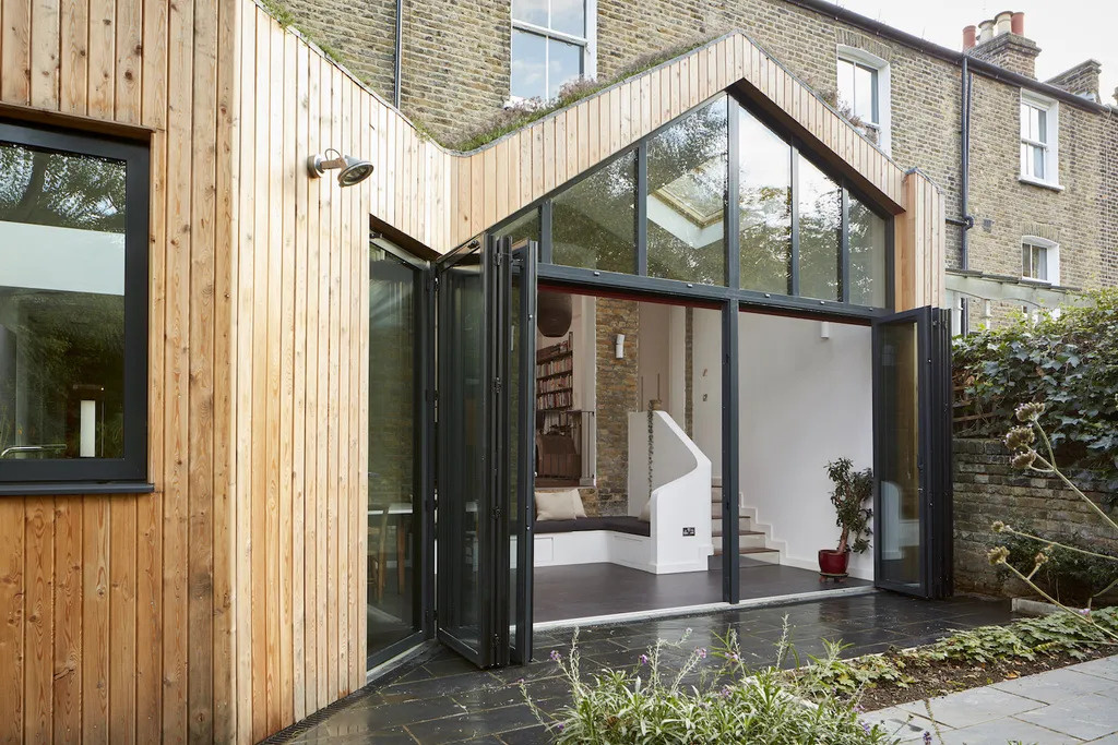 A timber clad extension with a green roof replaces a failing conservatory with a warm and light filled space that connects beautifully to the garden.