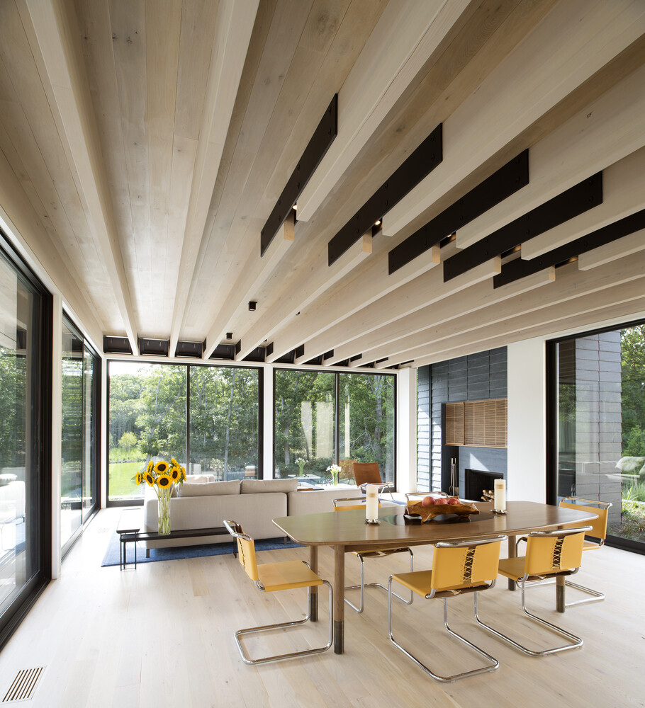 In this modern living room, exposed glulam beams and steel flitch plates form a structural system that is left visible and celebrated throughout the house.