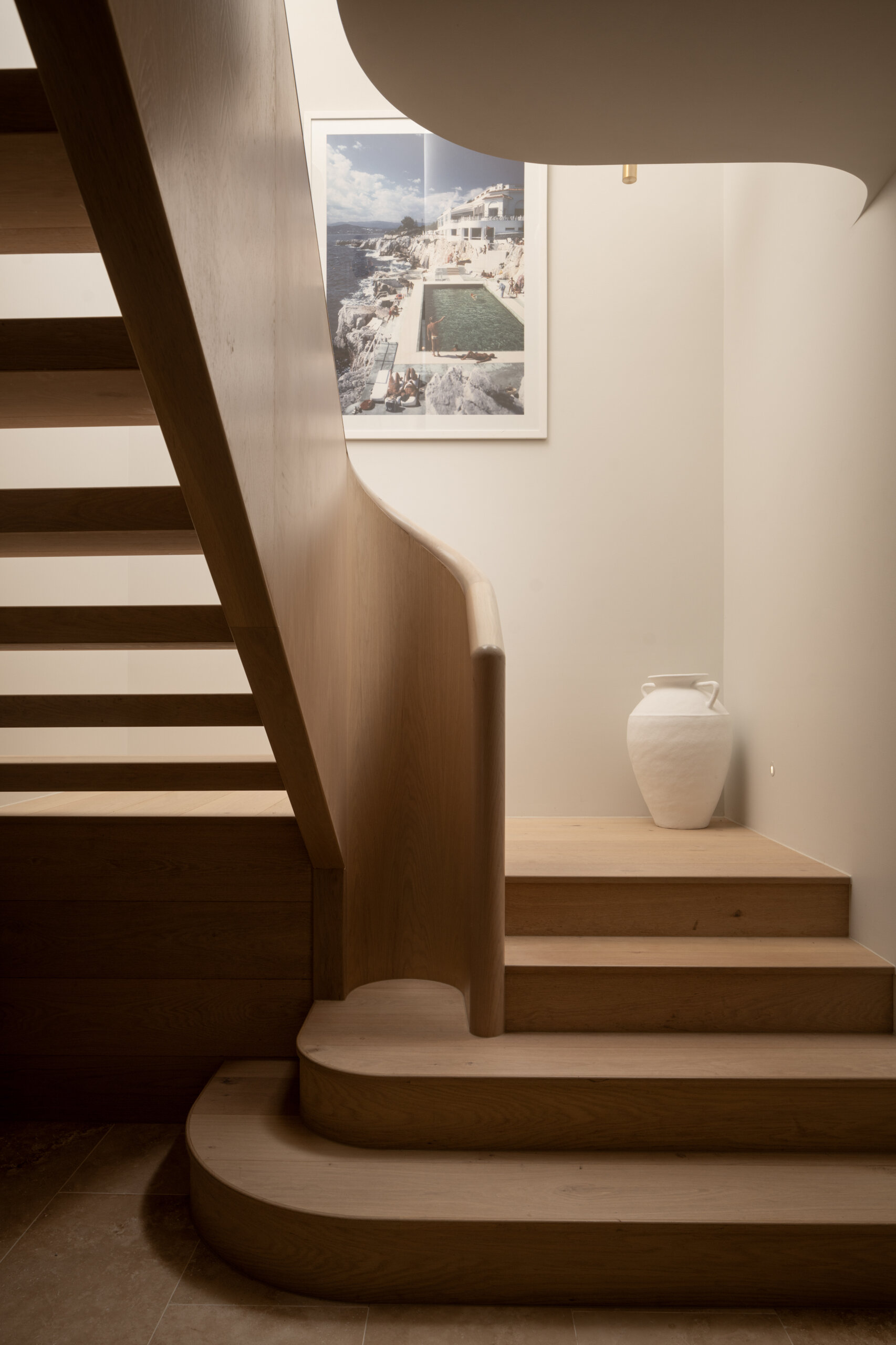 A curved oak and travertine staircase that mirrors the home’s soft Mediterranean lines.
