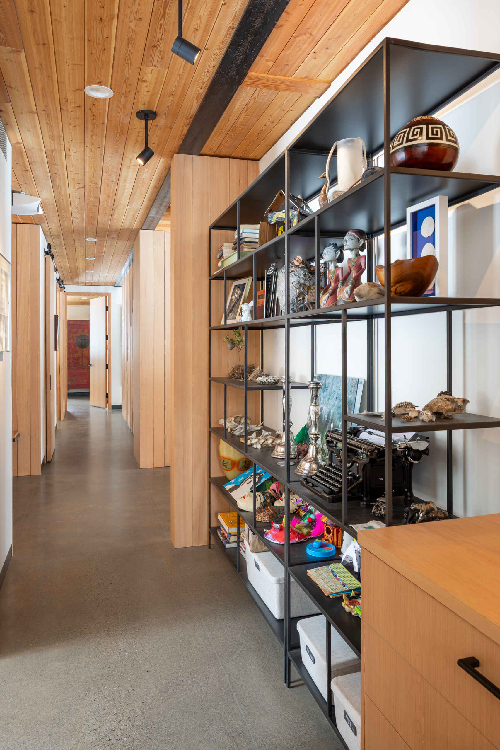 Modern hallway with a steel shelving unit that displays artwork.