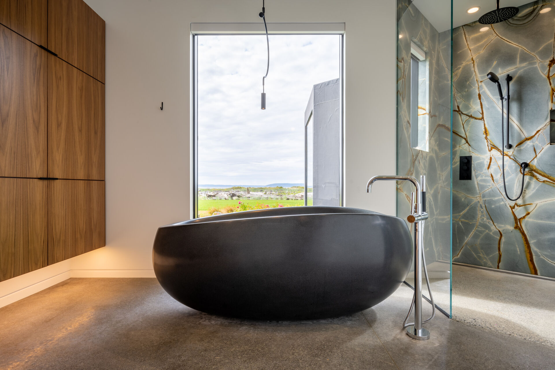 The primary bathroom includes a floating wood vanity with a freestanding sculptural black bathtub, and an eye-catching shower.
