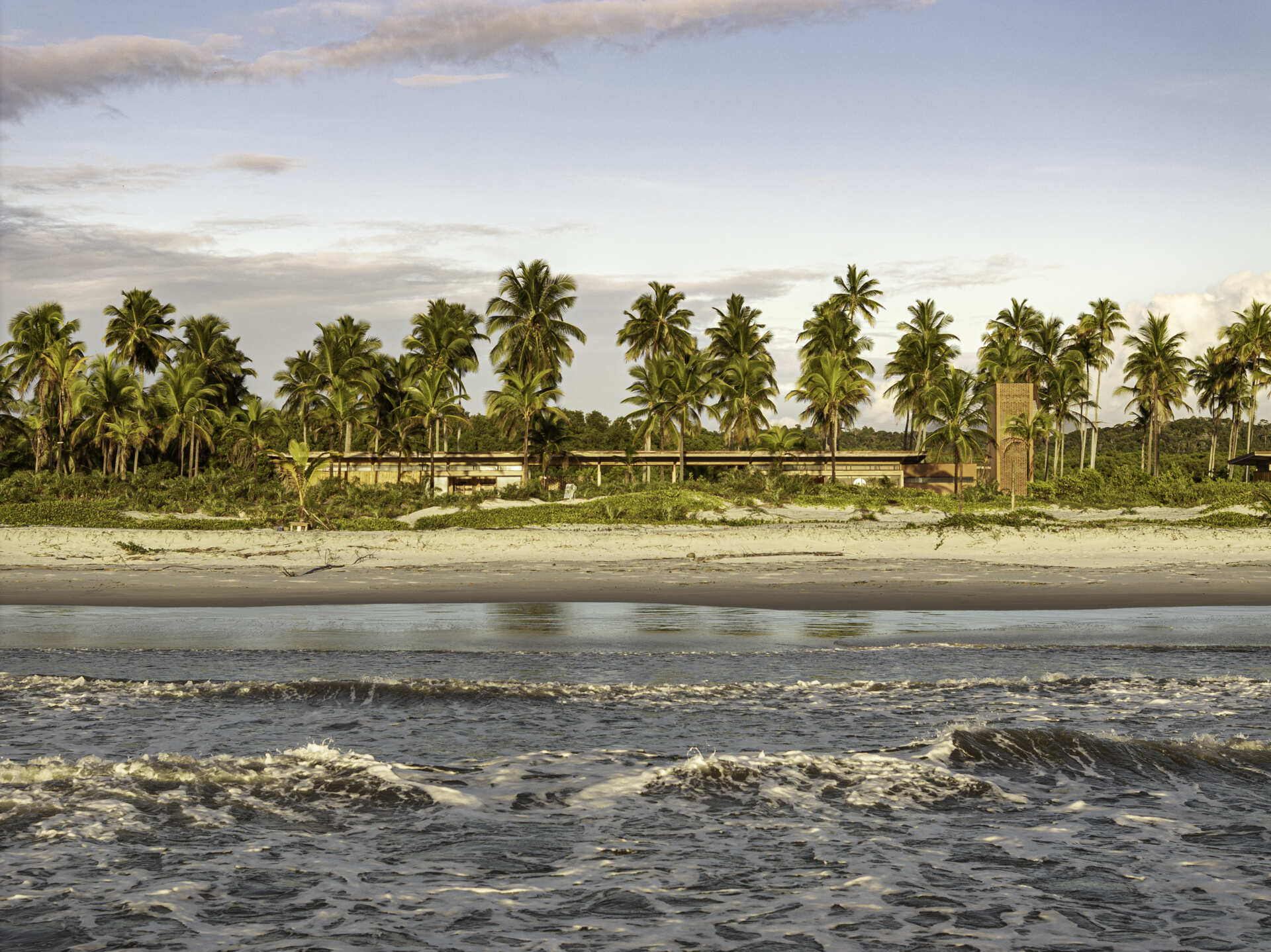 A modular home set between the river and the sea, designed for calm tropical living. Warm wood interiors, large glass openings, and open patios create a seamless flow between forest, coast, and indoor comfort.