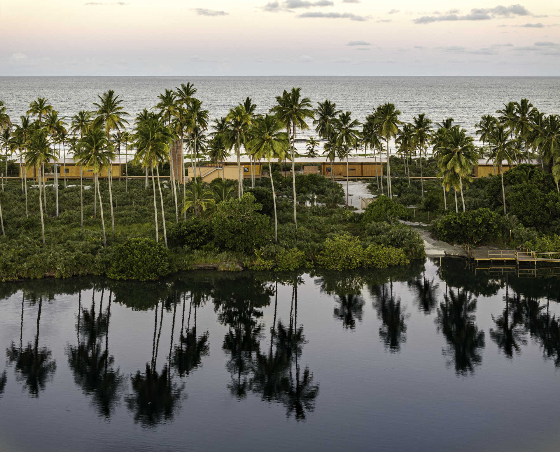 A modular home set between the river and the sea, designed for calm tropical living. Warm wood interiors, large glass openings, and open patios create a seamless flow between forest, coast, and indoor comfort.
