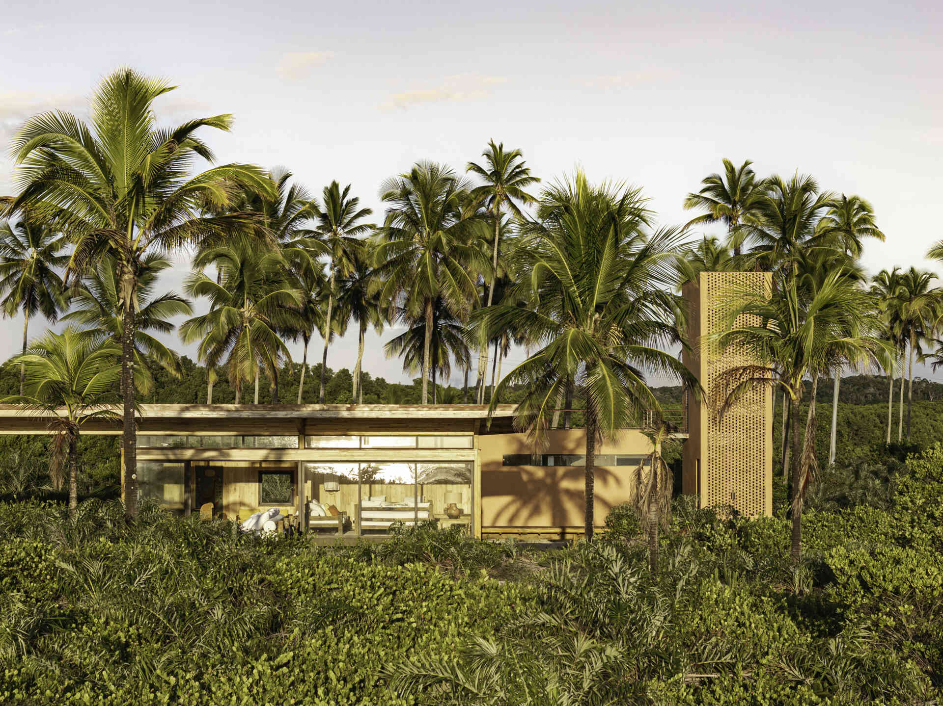 A modular home set between the river and the sea, designed for calm tropical living. Warm wood interiors, large glass openings, and open patios create a seamless flow between forest, coast, and indoor comfort.