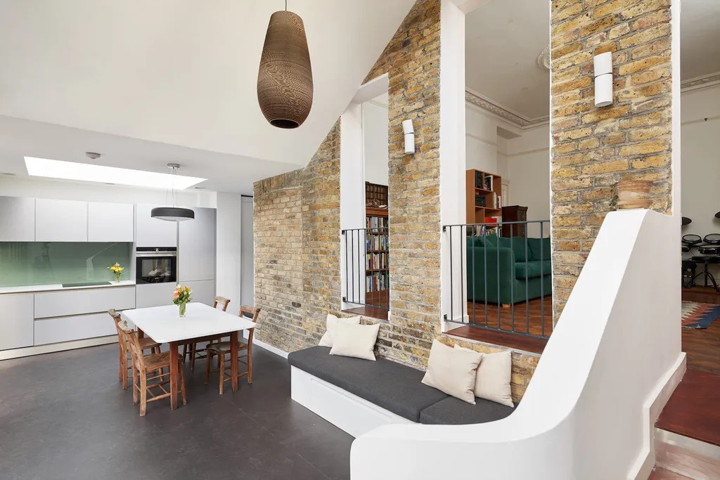 A raised Victorian living room looks down into the new extension creating a cosy lounge with a unique internal balcony feel.