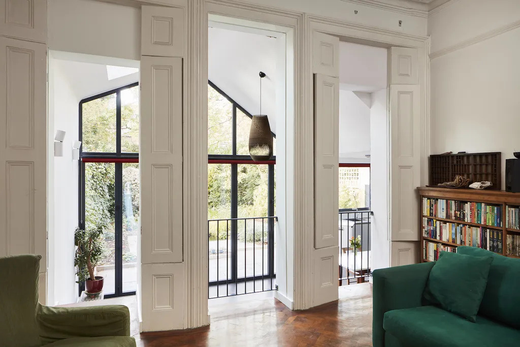 A raised Victorian living room looks down into the new extension creating a cosy lounge with a unique internal balcony feel.