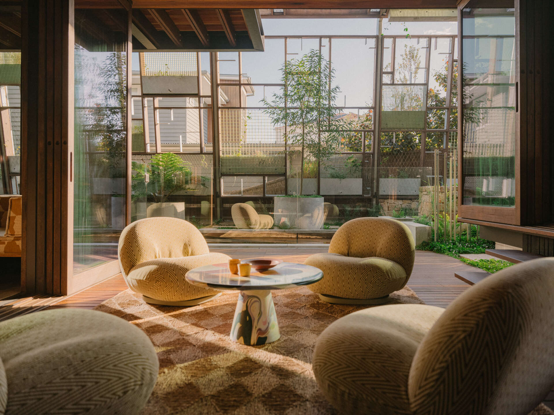 The deck runs beside the pool, forming a flowing outdoor living area. Protected by the plant canopy and open to air, wind and rain, it shifts with the weather.