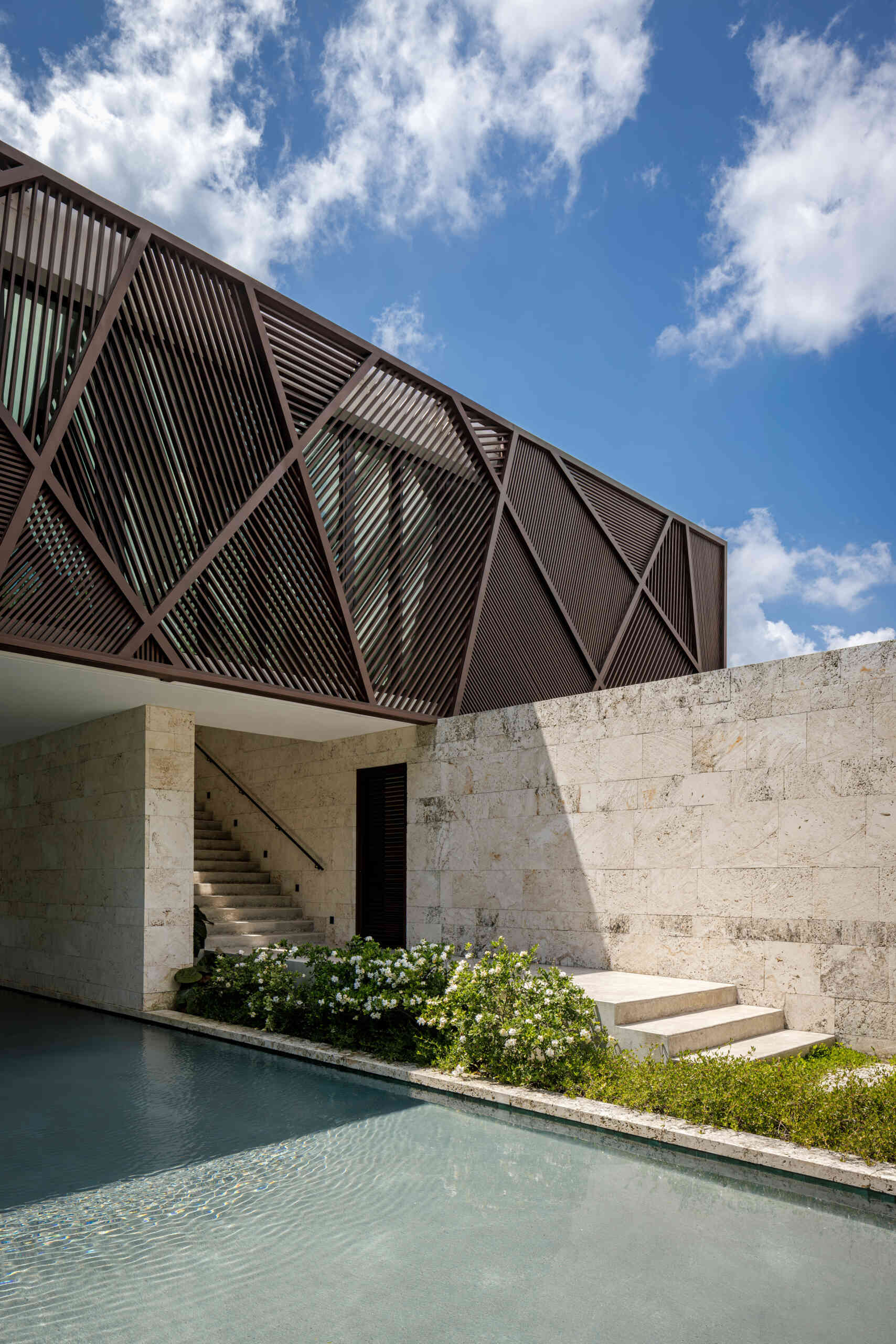 Wood panels and louvers wrap the upper level, providing sun control while introducing natural texture to the exterior.