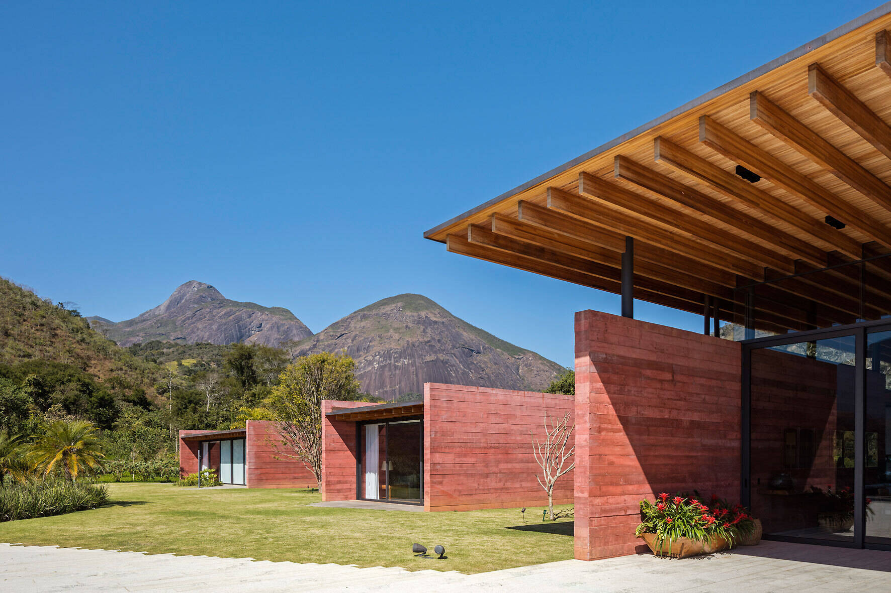 An exterior view of Casa Terra highlights the pigmented concrete walls, protruding volumes, and expansive timber roof.