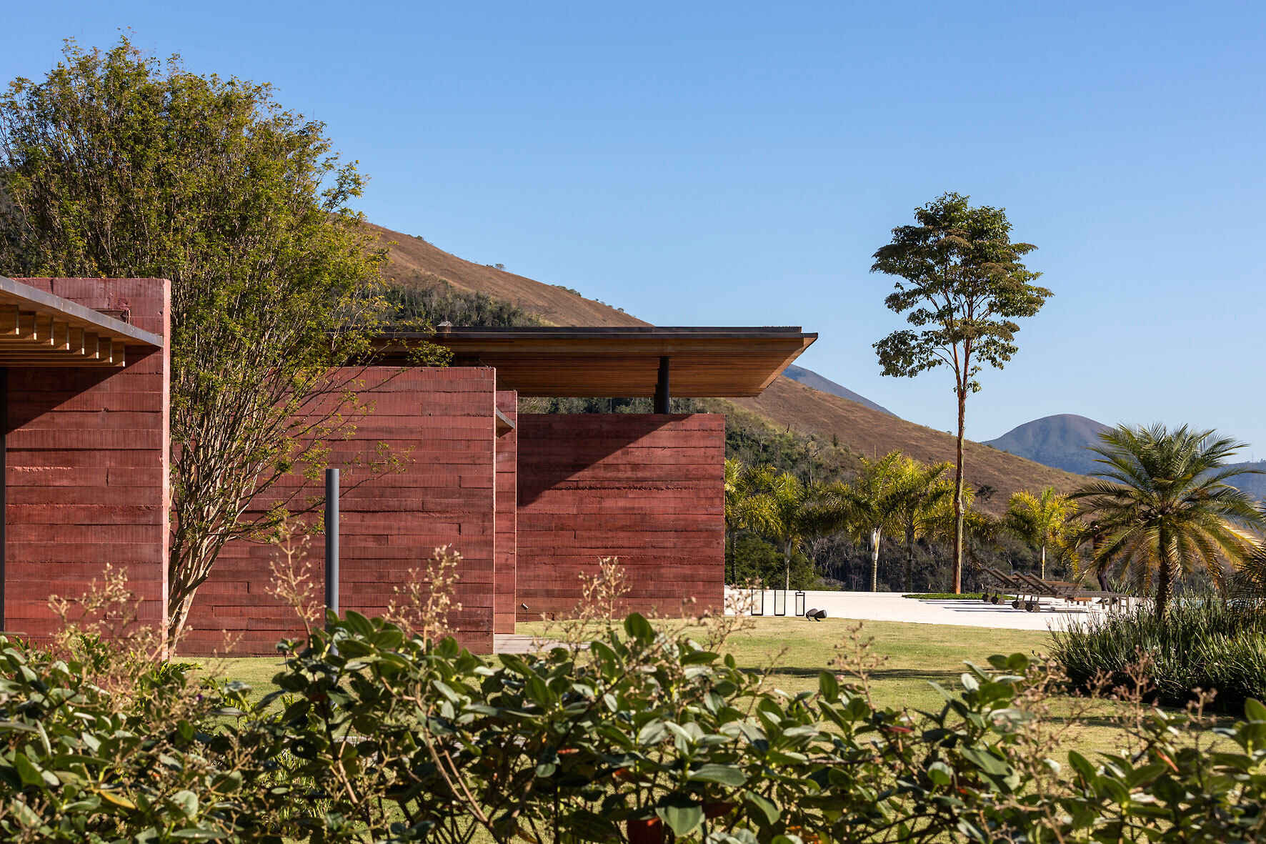 An exterior view of Casa Terra highlights the pigmented concrete walls, protruding volumes, and expansive timber roof.