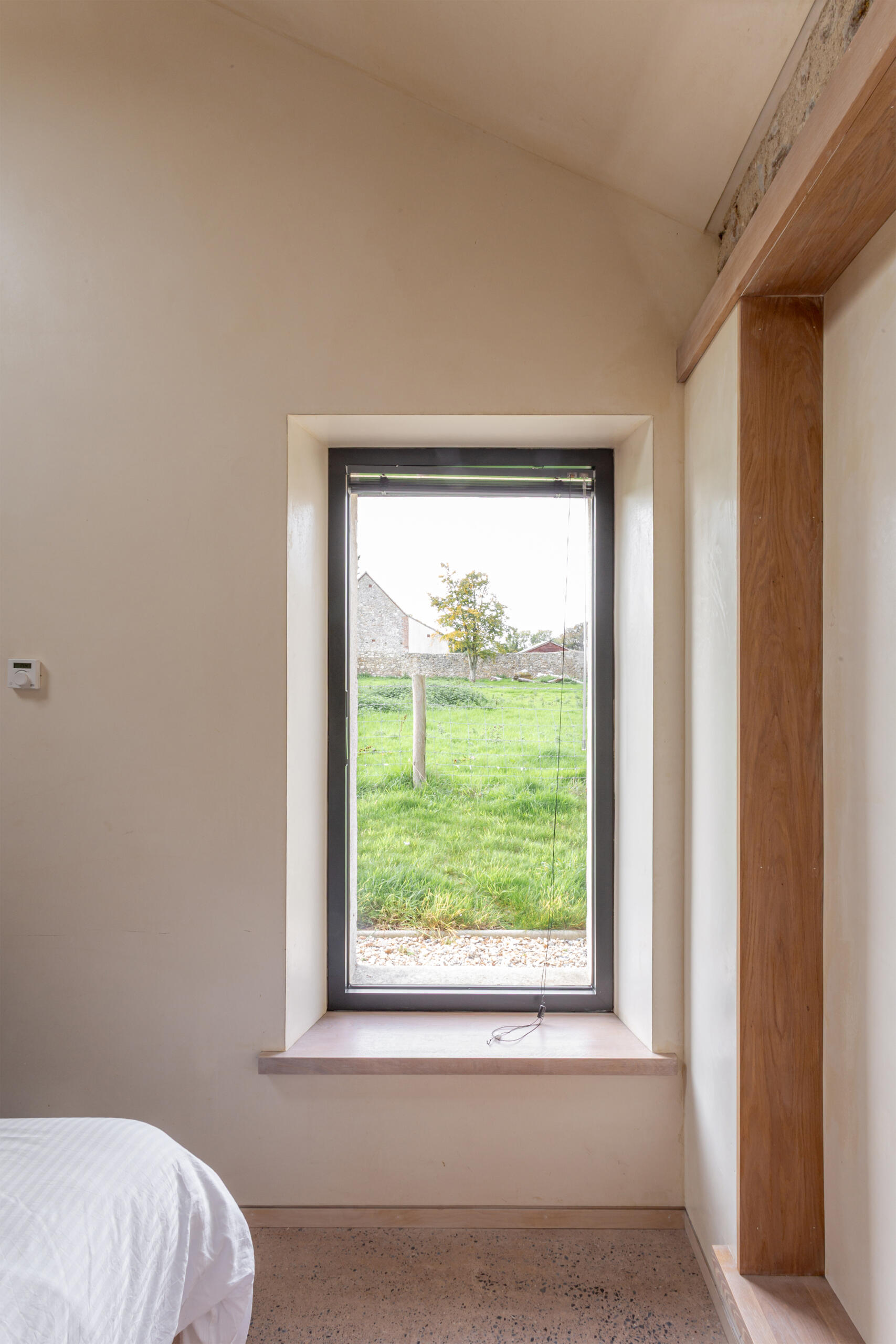 El dormitorio principal se encuentra dentro de la estructura de piedra restaurada. La profunda revelación crea un suave nicho para sentarse y reflexionar, y enmarca perfectamente las vistas al jardín.