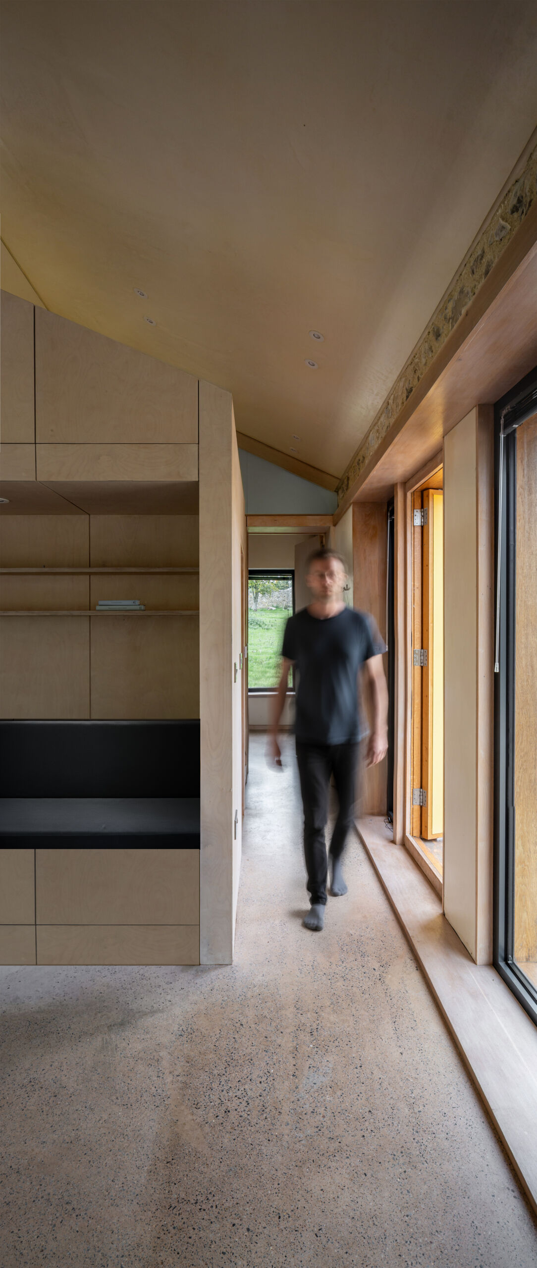 El hormigón pulido recorre toda la casa, aportando un suave tono rosado derivado de la tierra roja local. Este color ancla el interior y crea una cálida continuidad de un espacio al siguiente.