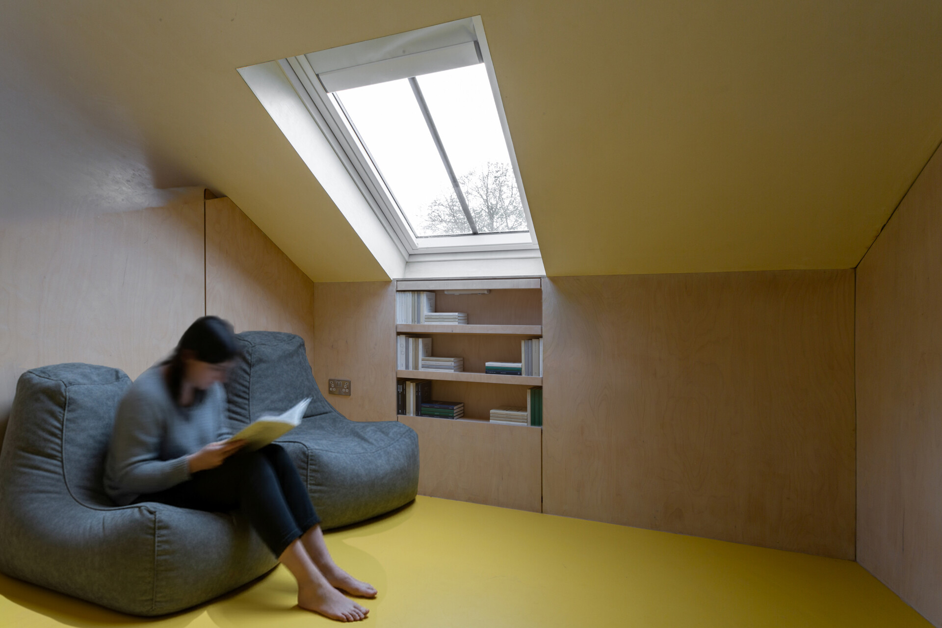 El entrepiso también funciona como rincón de lectura y espacio adicional para dormir. Los elementos incorporados de madera contrachapada mantienen el área liviana y funcional sin agregar volumen.