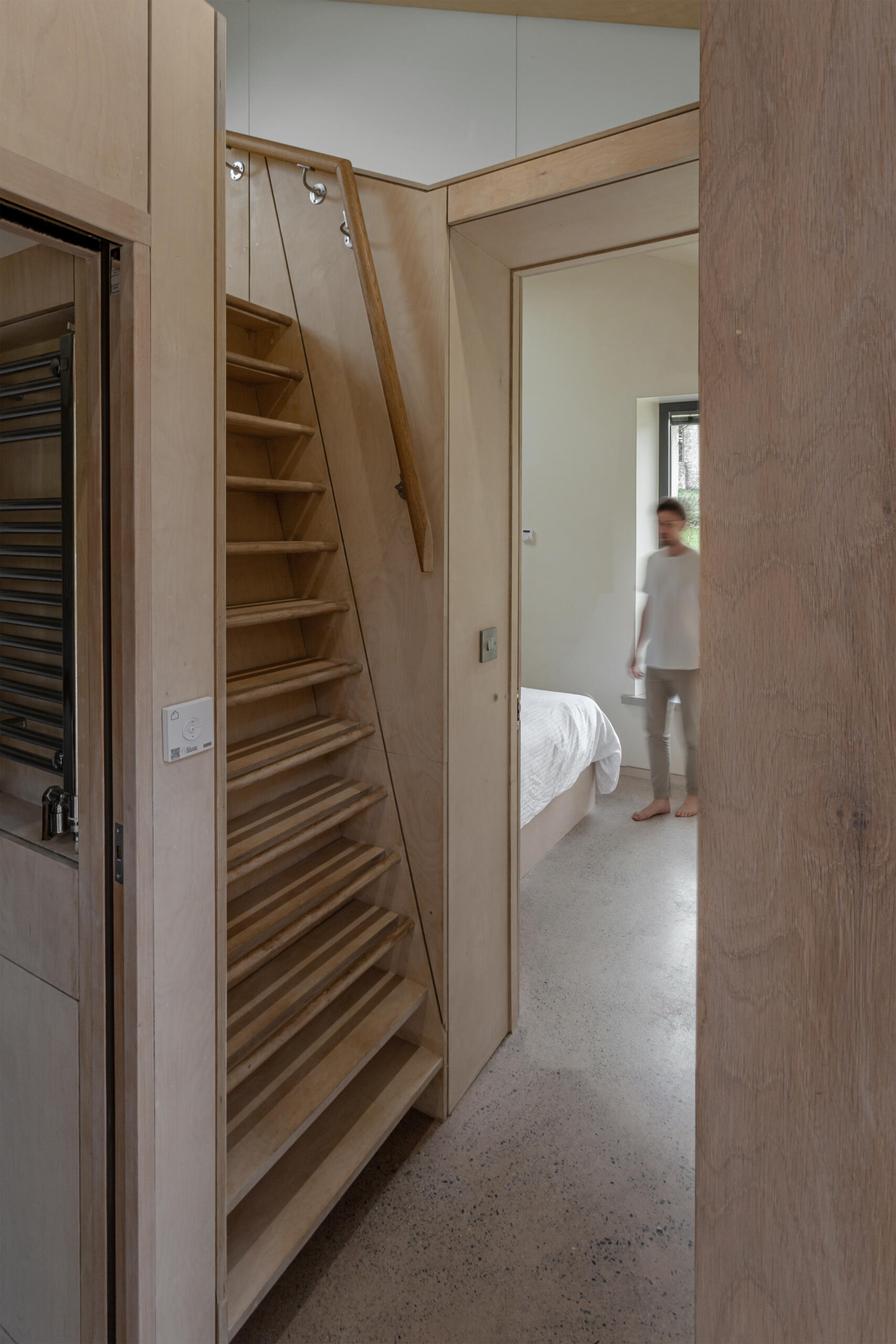 Una exquisita escalera de madera conduce al entrepiso. Es a la vez una línea práctica y una pieza de carpintería cuidadosamente elaborada que se adapta a la escala del interior.