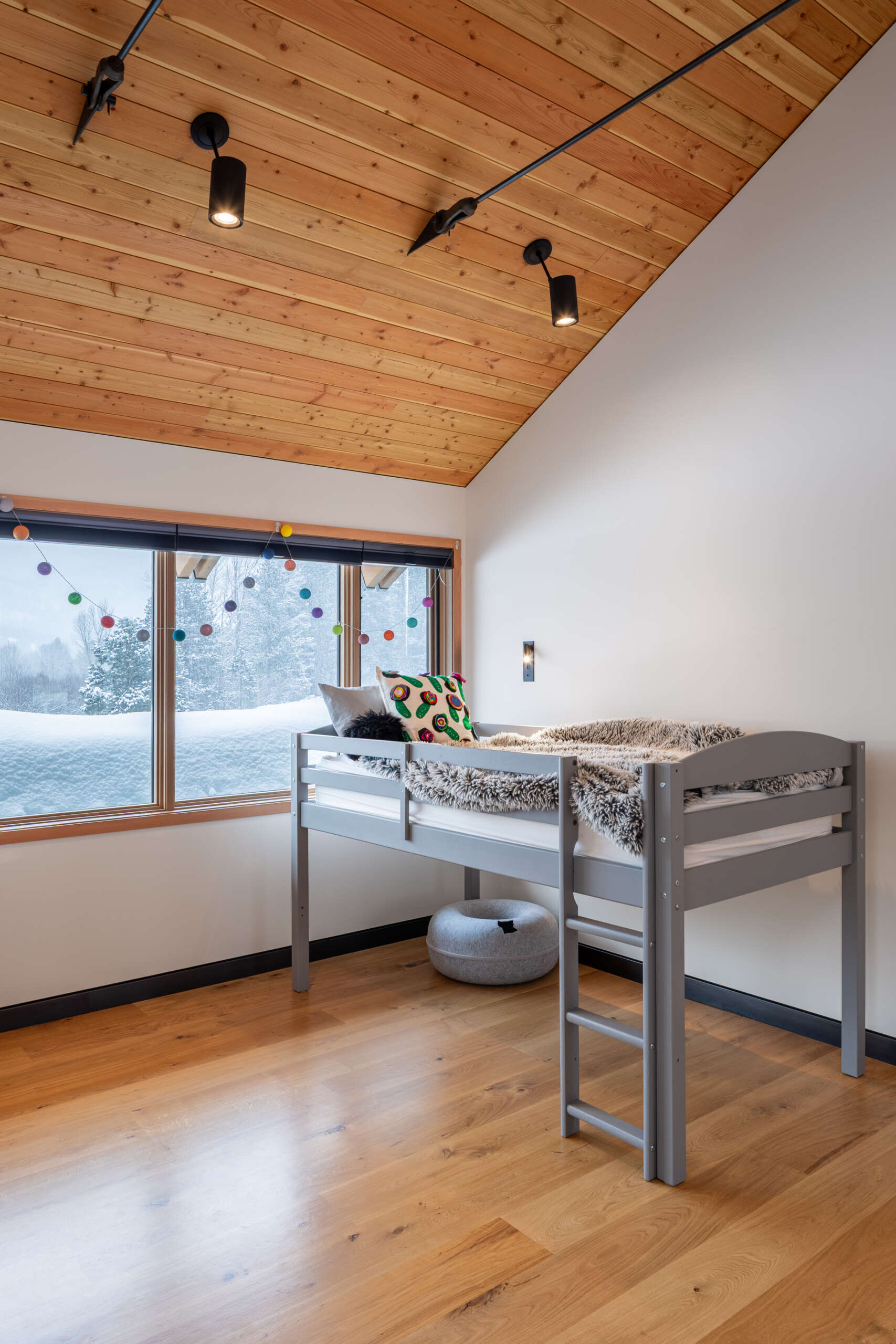 Simple, inviting bedrooms with warm wood ceilings, soft white walls, and thoughtful personal touches that create calm spaces connected to forest views.