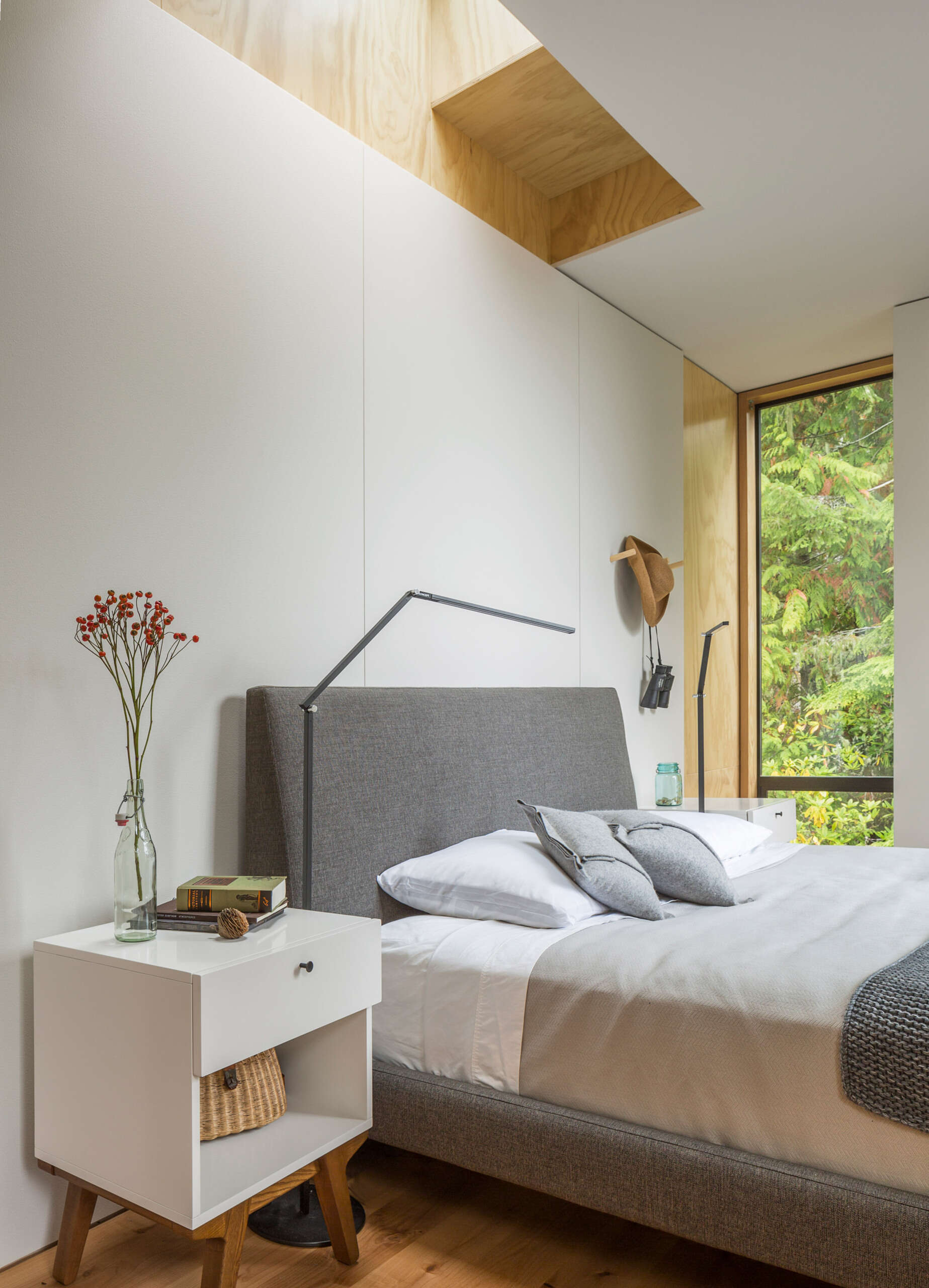A peaceful cabin bedroom with a skylight above the bed and a softly lit white interior.