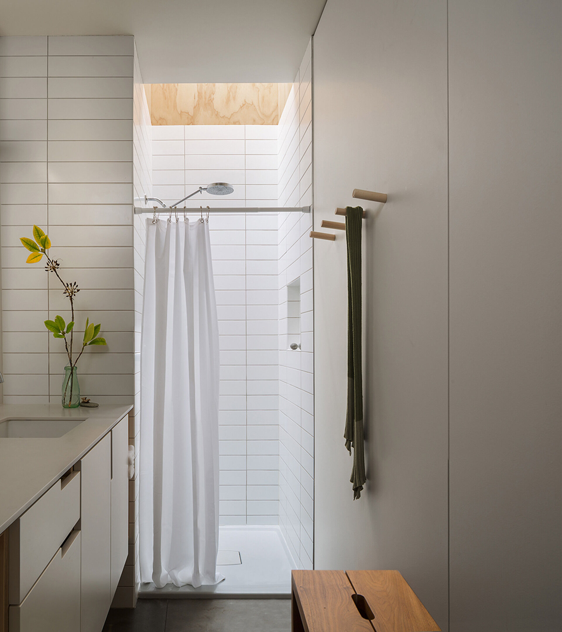 A modern skylit bathroom with long white tiles and a fresh, streamlined design.