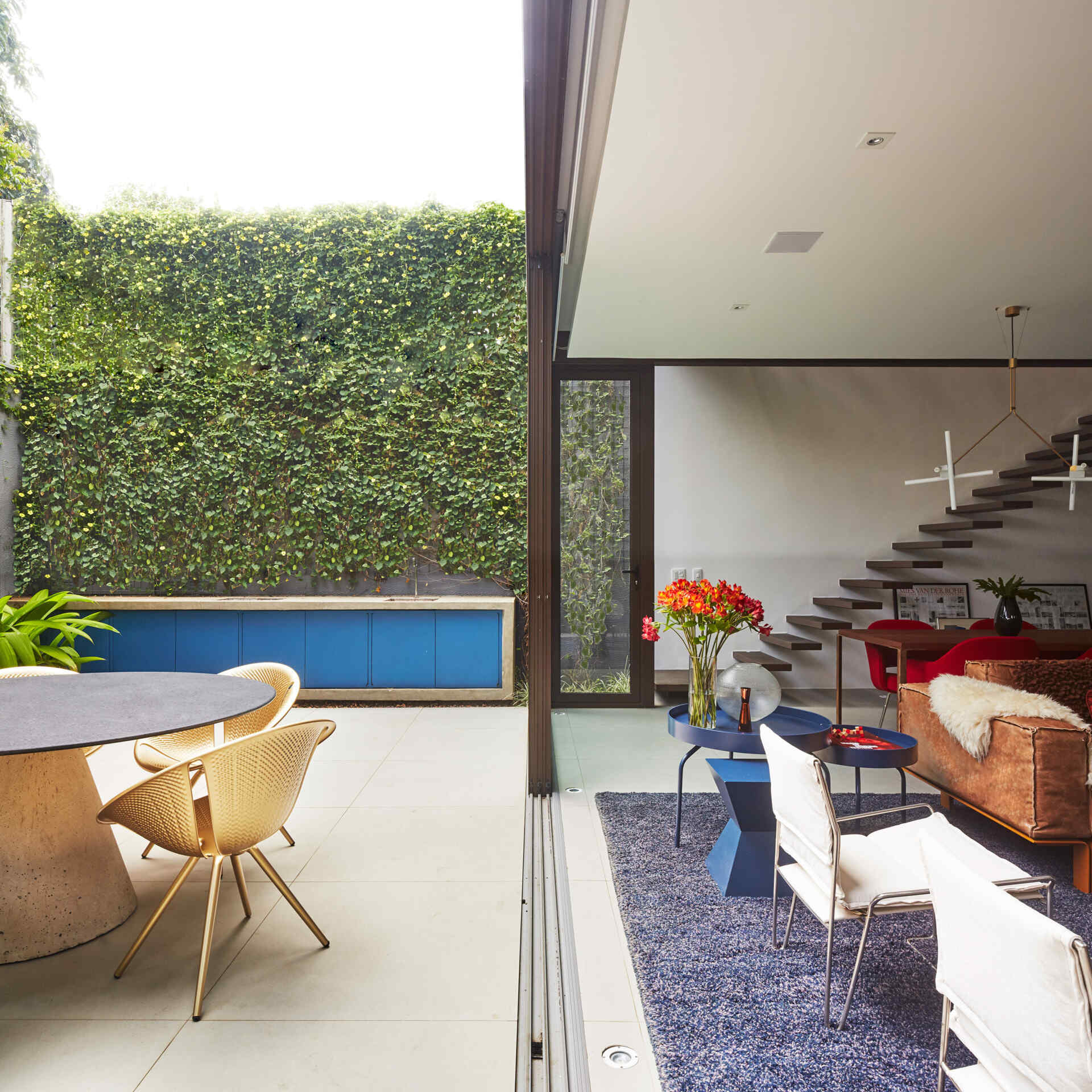 Along one side of the interior, floating stairs lead to the upper floor. Their light construction reinforces the sense of openness, guiding movement upward without visually interrupting the space below.