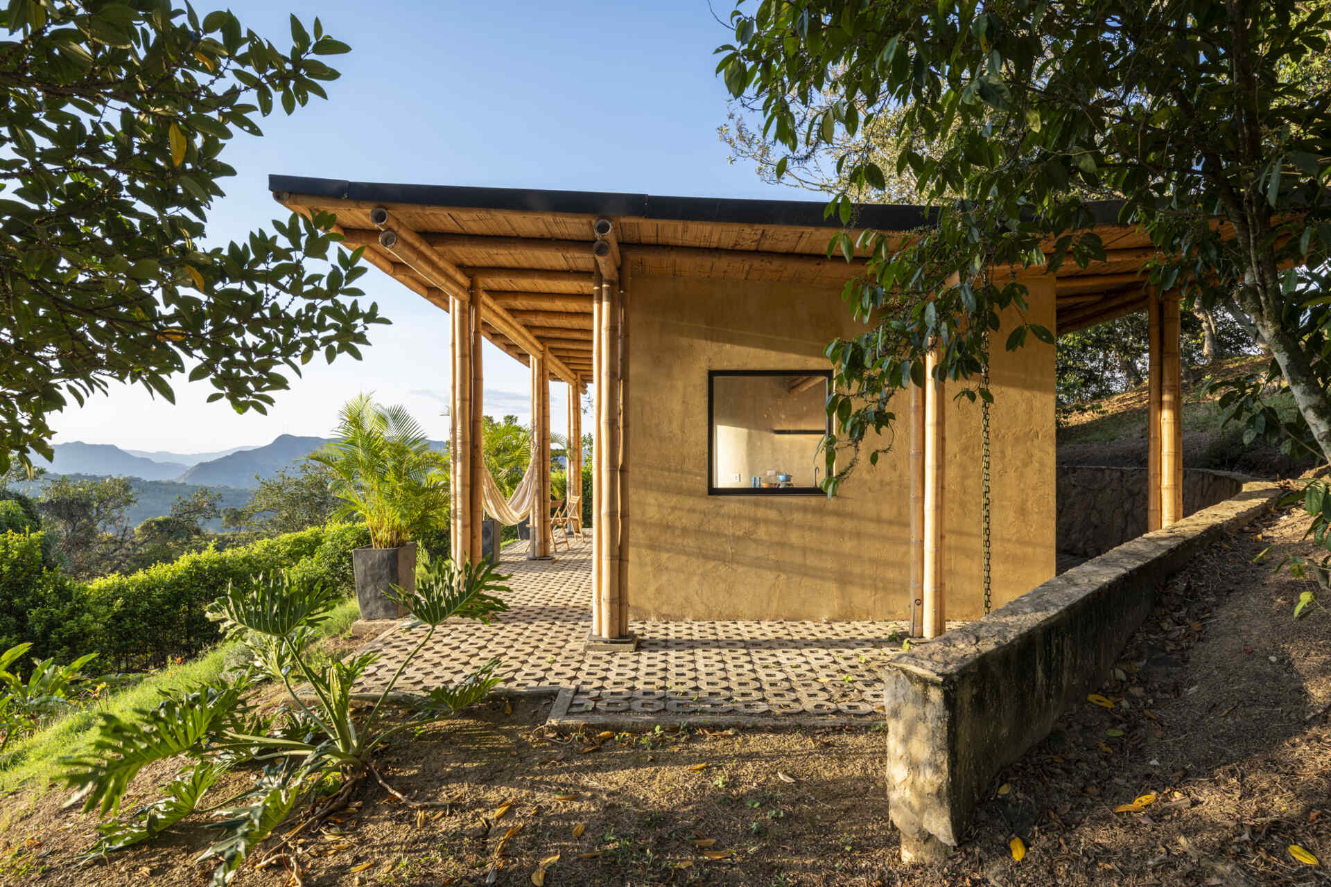 This Colombian home reimagines rural architecture with a butterfly roof that collects rainwater, bamboo-and-steel structural details, and an open interior where the bedroom, kitchenette, and a hidden curved-wall bathroom blend seamlessly, creating a sustainable, modern, and deeply connected living experience.