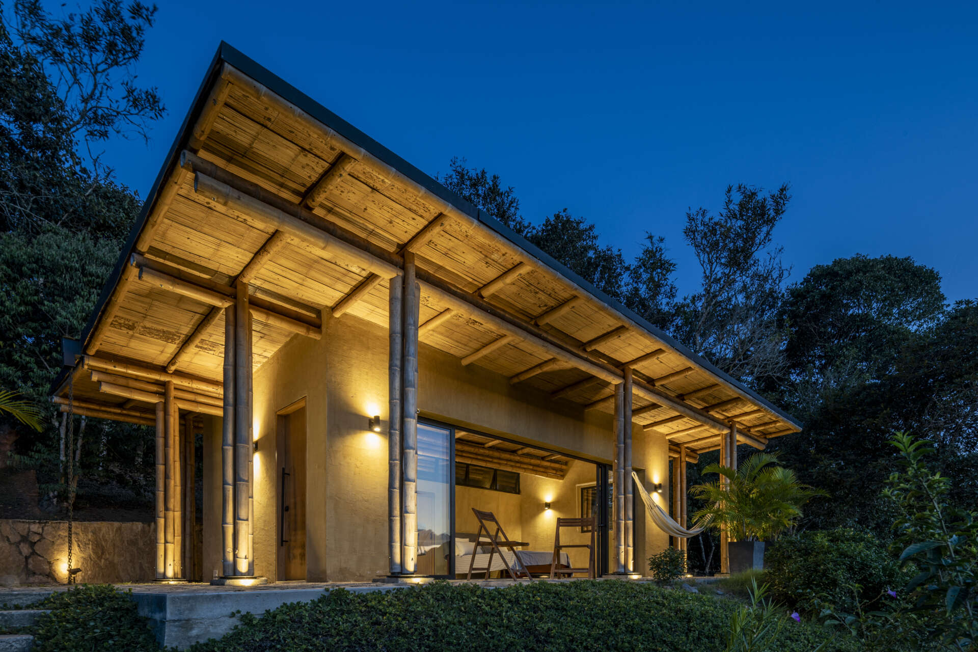 This Colombian home reimagines rural architecture with a butterfly roof that collects rainwater, bamboo-and-steel structural details, and an open interior where the bedroom, kitchenette, and a hidden curved-wall bathroom blend seamlessly, creating a sustainable, modern, and deeply connected living experience.