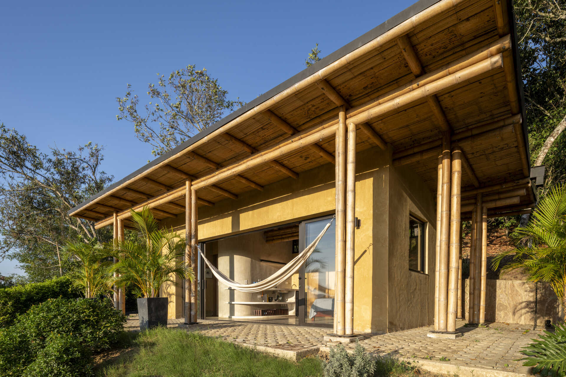 This Colombian home reimagines rural architecture with a butterfly roof that collects rainwater, bamboo-and-steel structural details, and an open interior where the bedroom, kitchenette, and a hidden curved-wall bathroom blend seamlessly, creating a sustainable, modern, and deeply connected living experience.