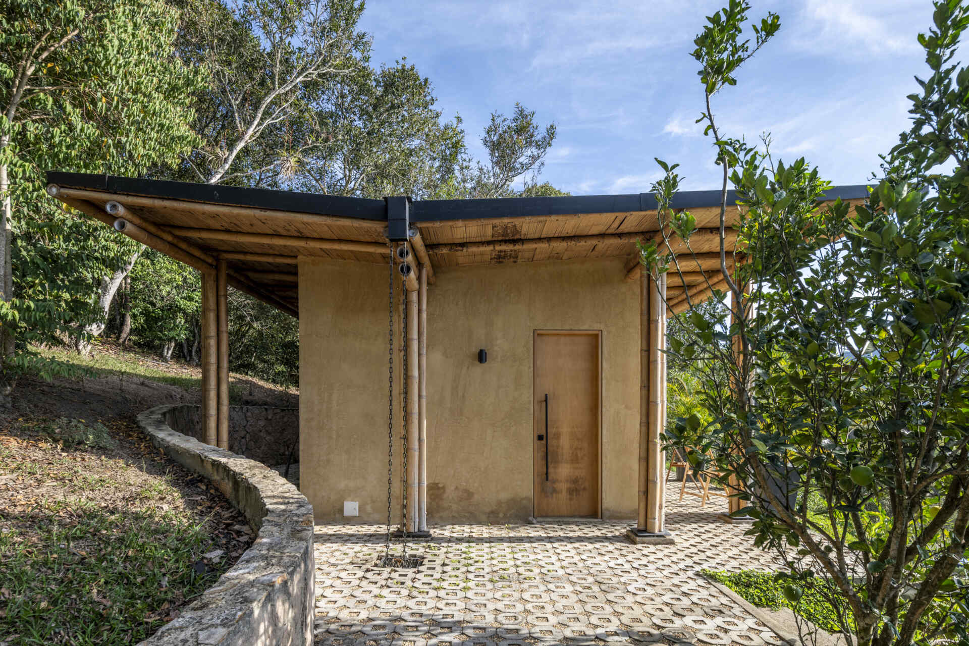 This Colombian home reimagines rural architecture with a butterfly roof that collects rainwater, bamboo-and-steel structural details, and an open interior where the bedroom, kitchenette, and a hidden curved-wall bathroom blend seamlessly, creating a sustainable, modern, and deeply connected living experience.