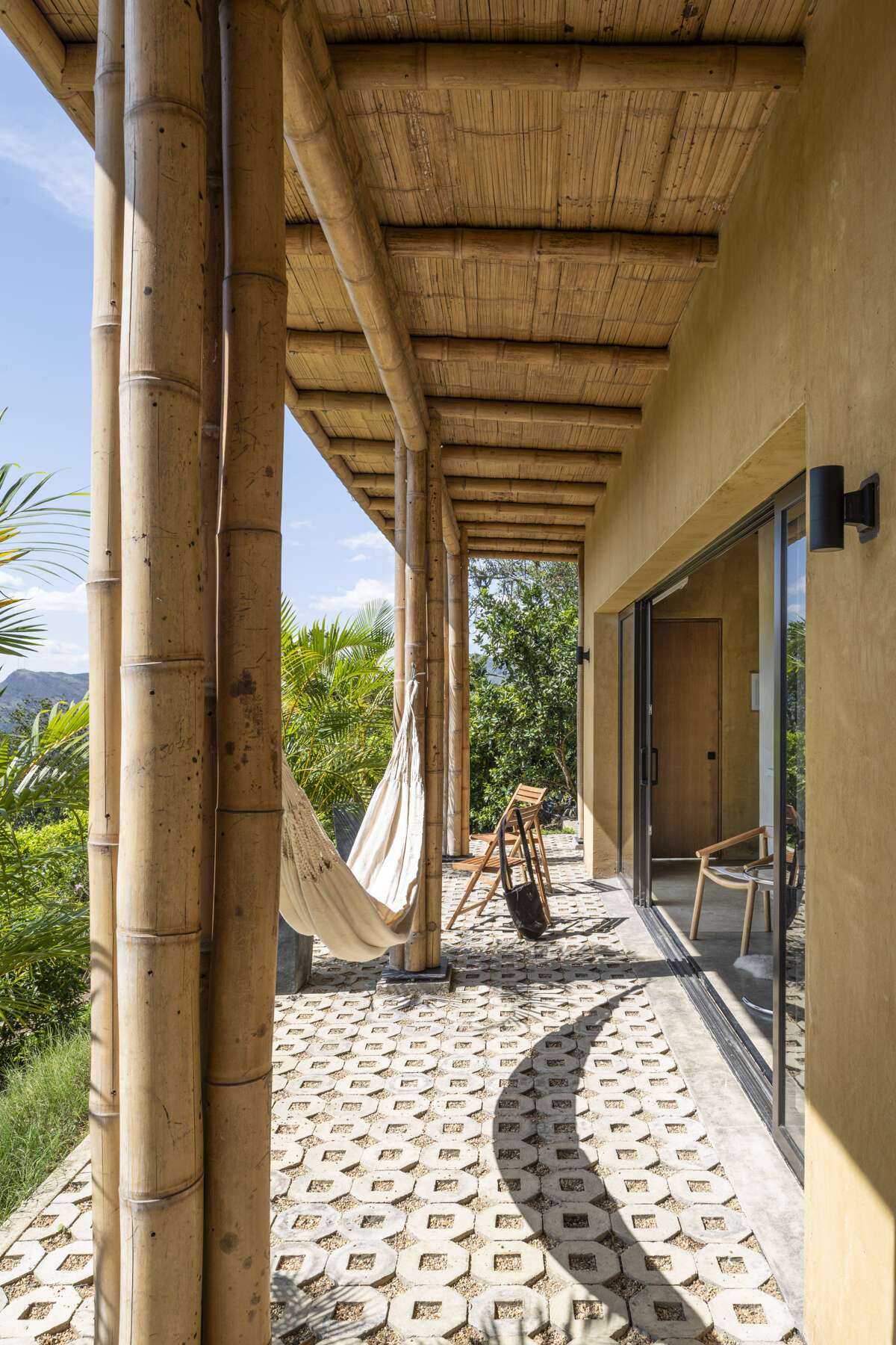 This Colombian home reimagines rural architecture with a butterfly roof that collects rainwater, bamboo-and-steel structural details, and an open interior where the bedroom, kitchenette, and a hidden curved-wall bathroom blend seamlessly, creating a sustainable, modern, and deeply connected living experience.
