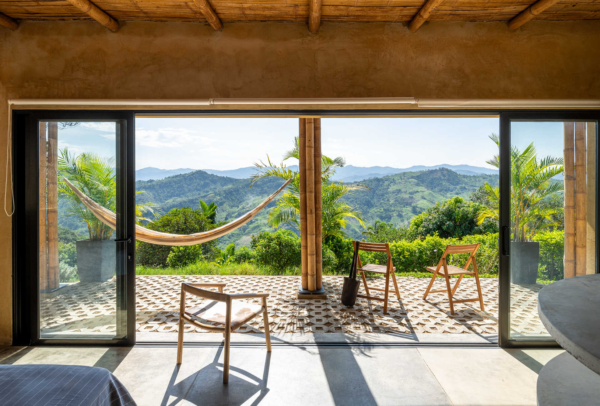 This Colombian home reimagines rural architecture with a butterfly roof that collects rainwater, bamboo-and-steel structural details, and an open interior where the bedroom, kitchenette, and a hidden curved-wall bathroom blend seamlessly, creating a sustainable, modern, and deeply connected living experience.