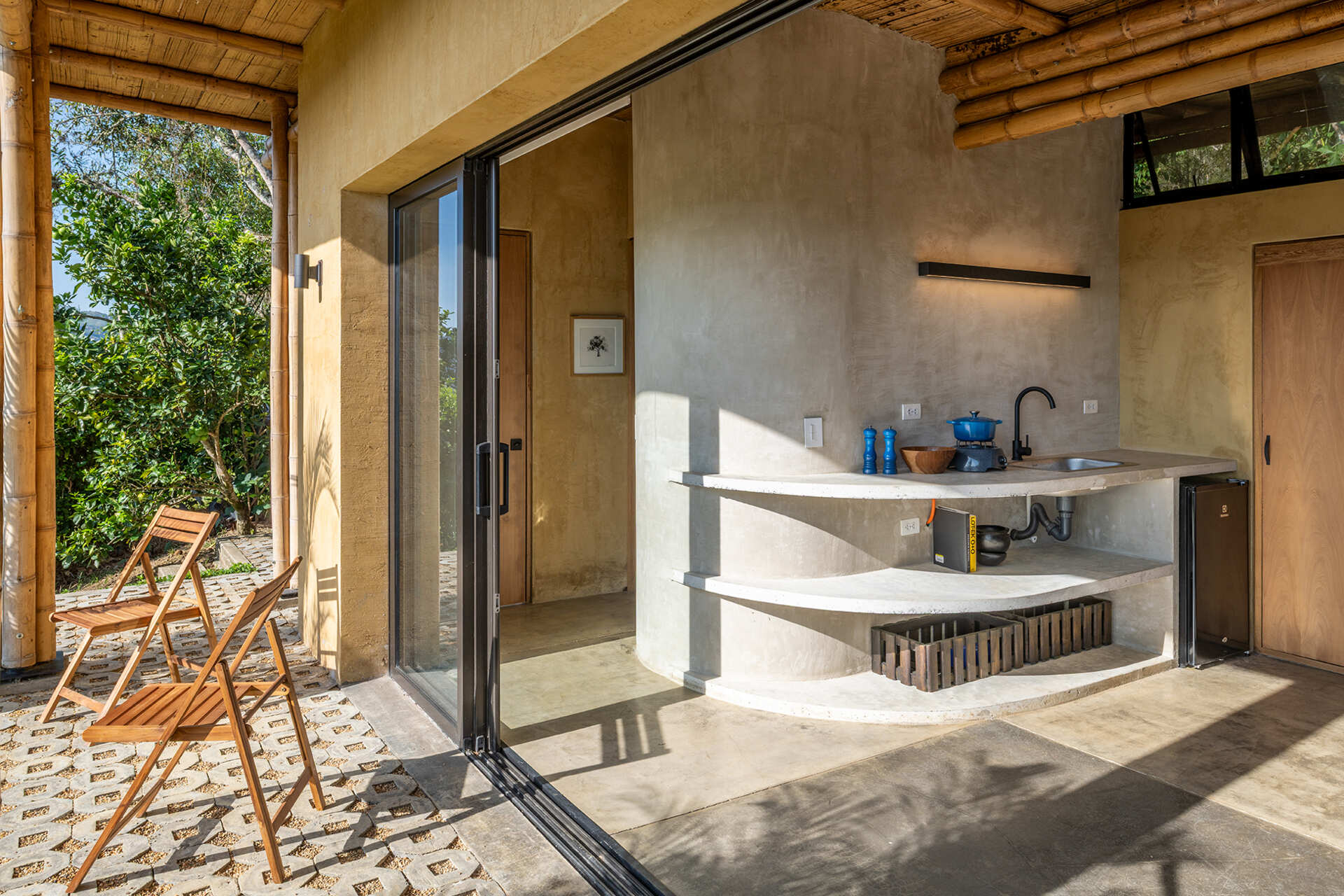 This Colombian home reimagines rural architecture with a butterfly roof that collects rainwater, bamboo-and-steel structural details, and an open interior where the bedroom, kitchenette, and a hidden curved-wall bathroom blend seamlessly, creating a sustainable, modern, and deeply connected living experience.