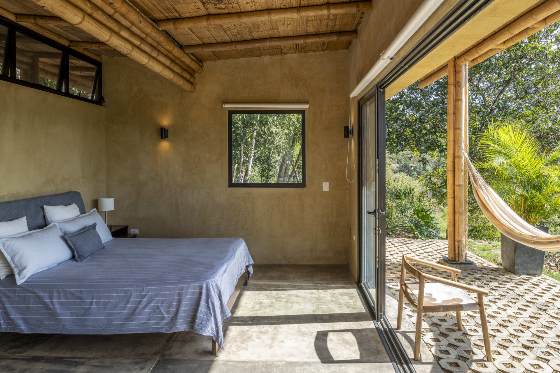 This Colombian home reimagines rural architecture with a butterfly roof that collects rainwater, bamboo-and-steel structural details, and an open interior where the bedroom, kitchenette, and a hidden curved-wall bathroom blend seamlessly, creating a sustainable, modern, and deeply connected living experience.