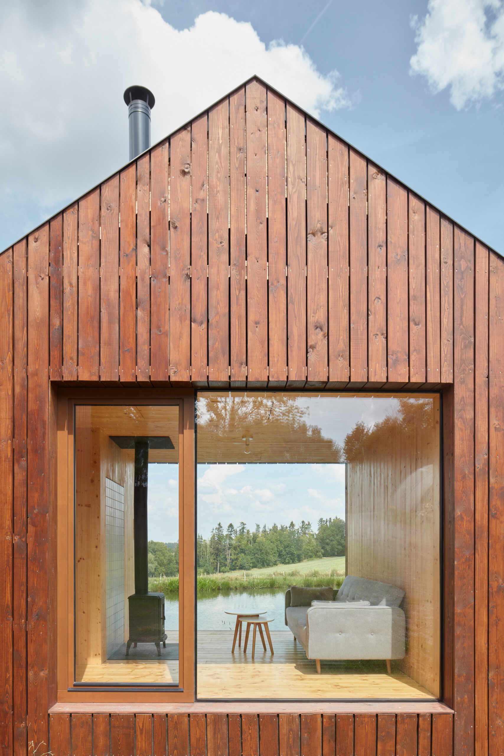 El diseño inteligente de la cabina está inspirado en las tradicionales cabañas de pescadores, integrando los interiores con vistas al estanque y un entorno de roble iluminado por el sol.