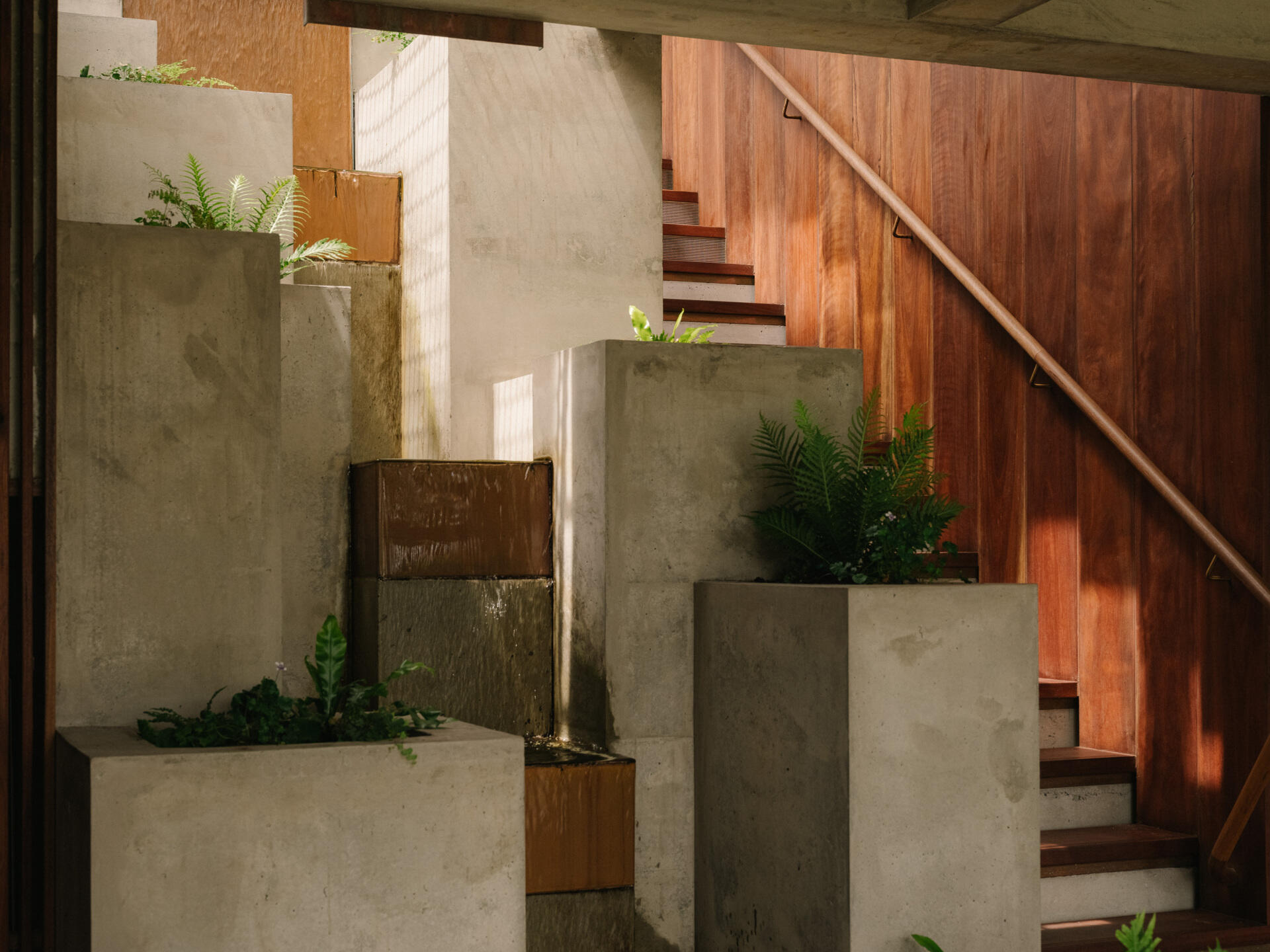 Cross a pond, step on stones, and ascend alongside a cascading waterfall to enter the living spaces.