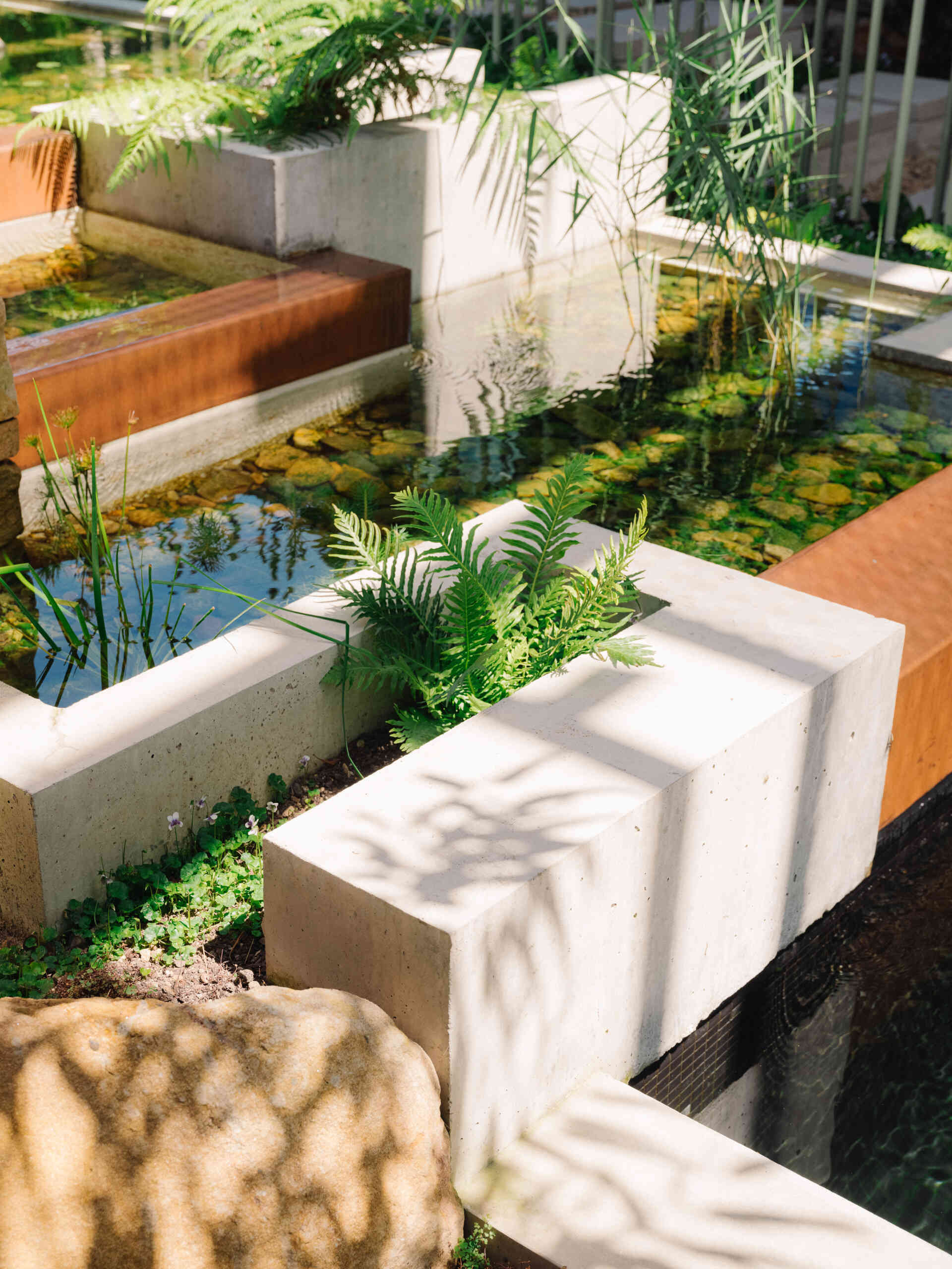 Cross a pond, step on stones, and ascend alongside a cascading waterfall to enter the living spaces.