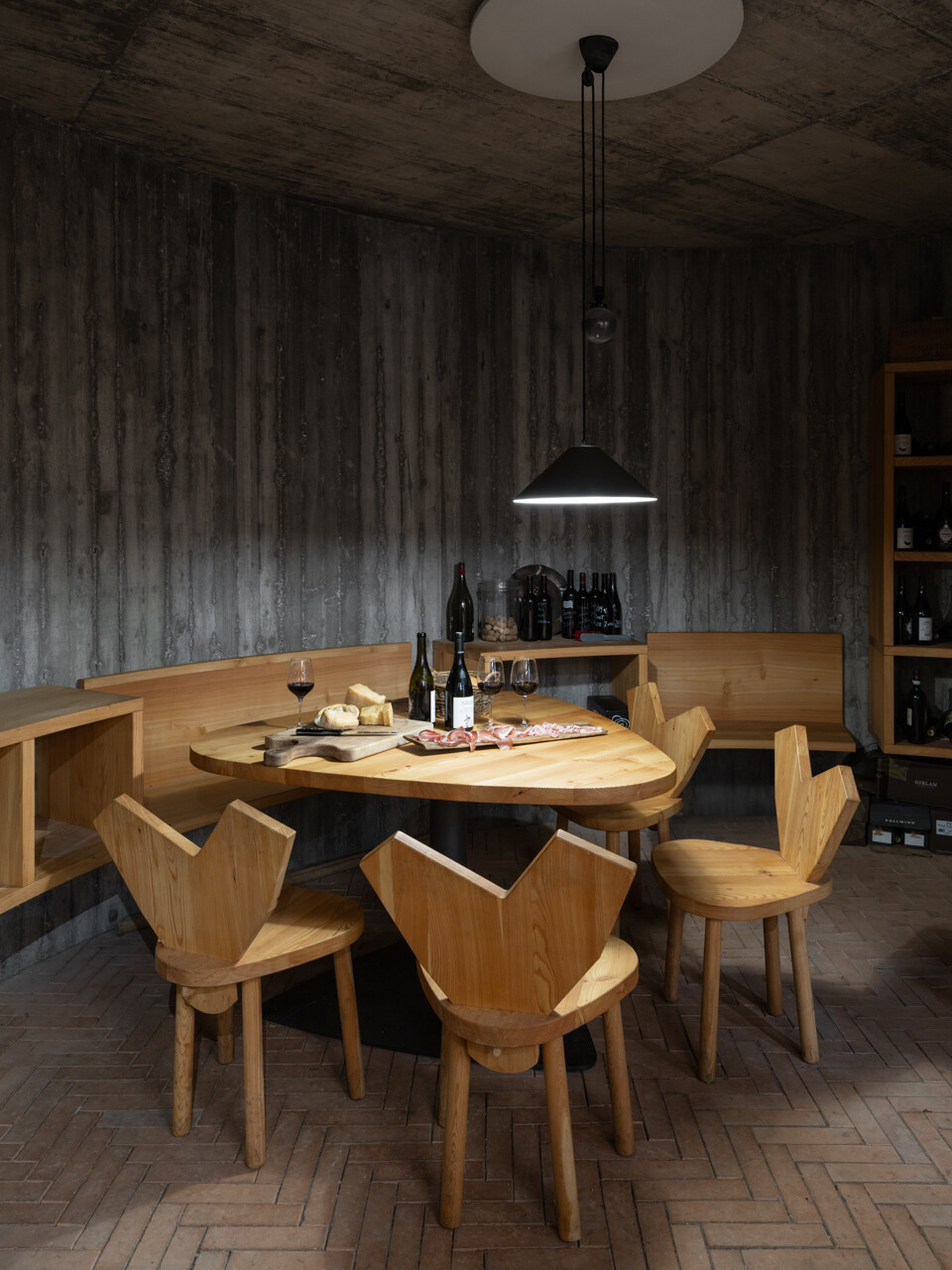 An underground wine cellar with curved concrete walls and brick floors anchors the home to land and memory.