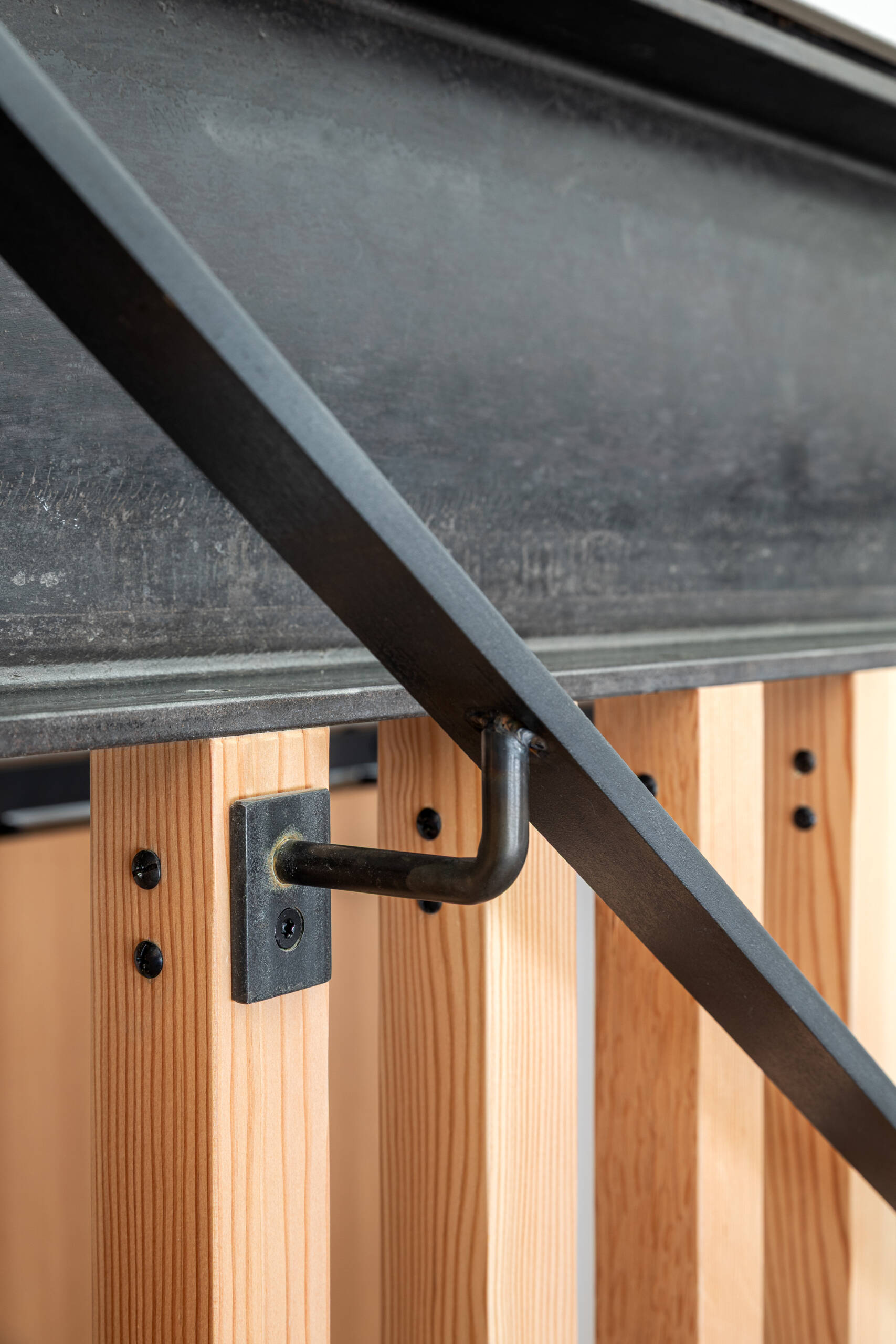 A sculptural stairway with black steel treads and a vertical wood slat screen, allowing light to move freely while adding texture and architectural interest.