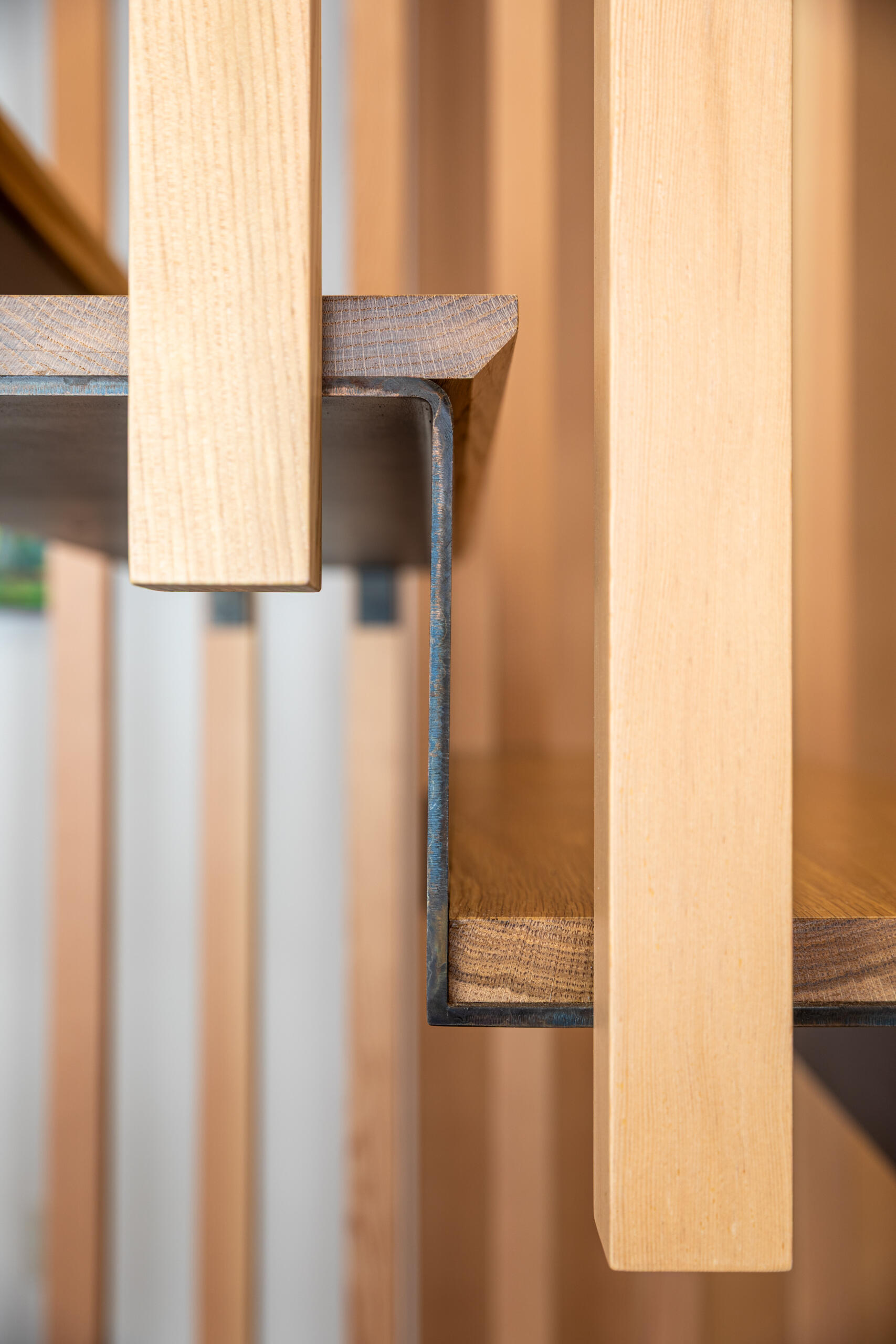 A sculptural stairway with black steel treads and a vertical wood slat screen, allowing light to move freely while adding texture and architectural interest.