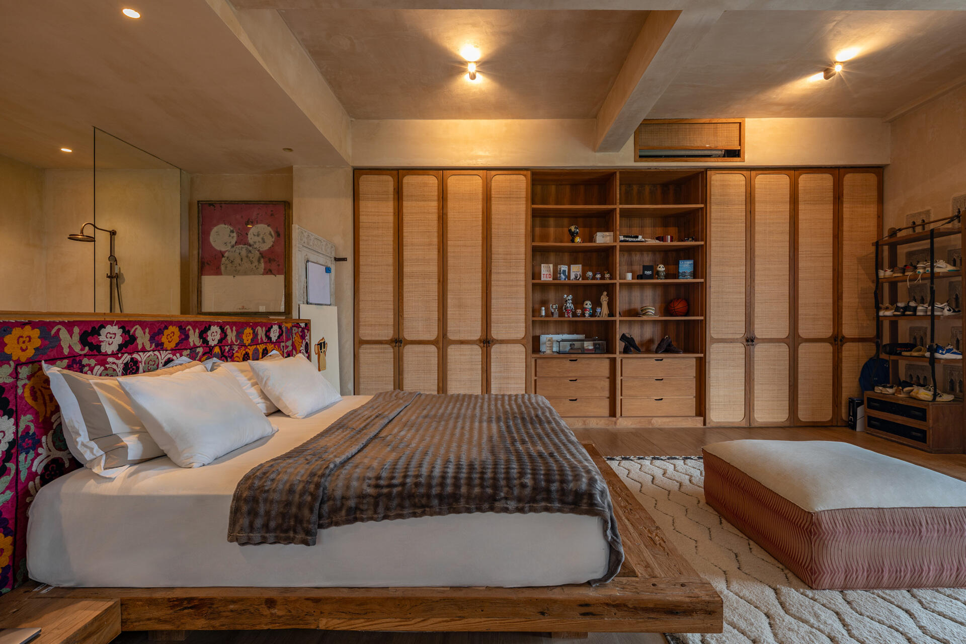 A contemporary bedroom with a built-in closet system, and an open bathroom.