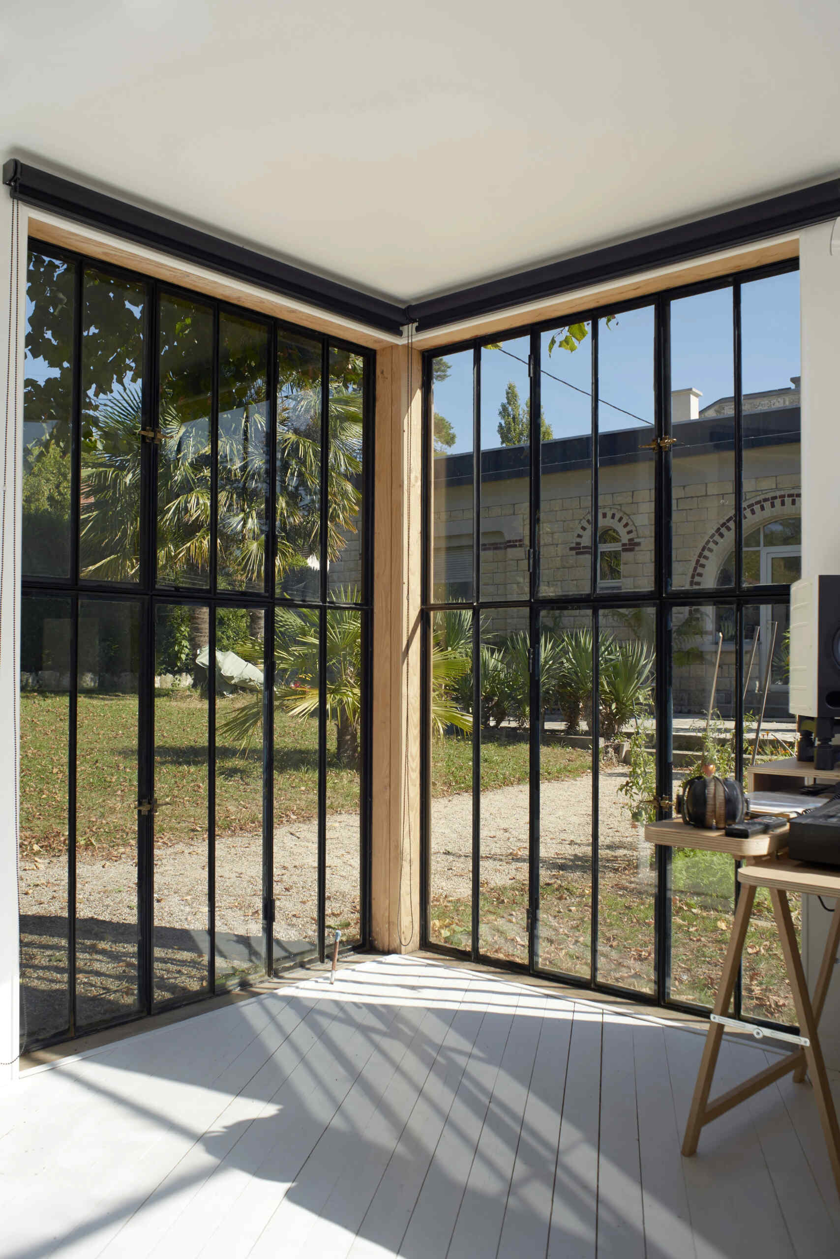 Black-framed windows are positioned to frame views of the vegetable garden, a 1940s house, and a centennial oak.