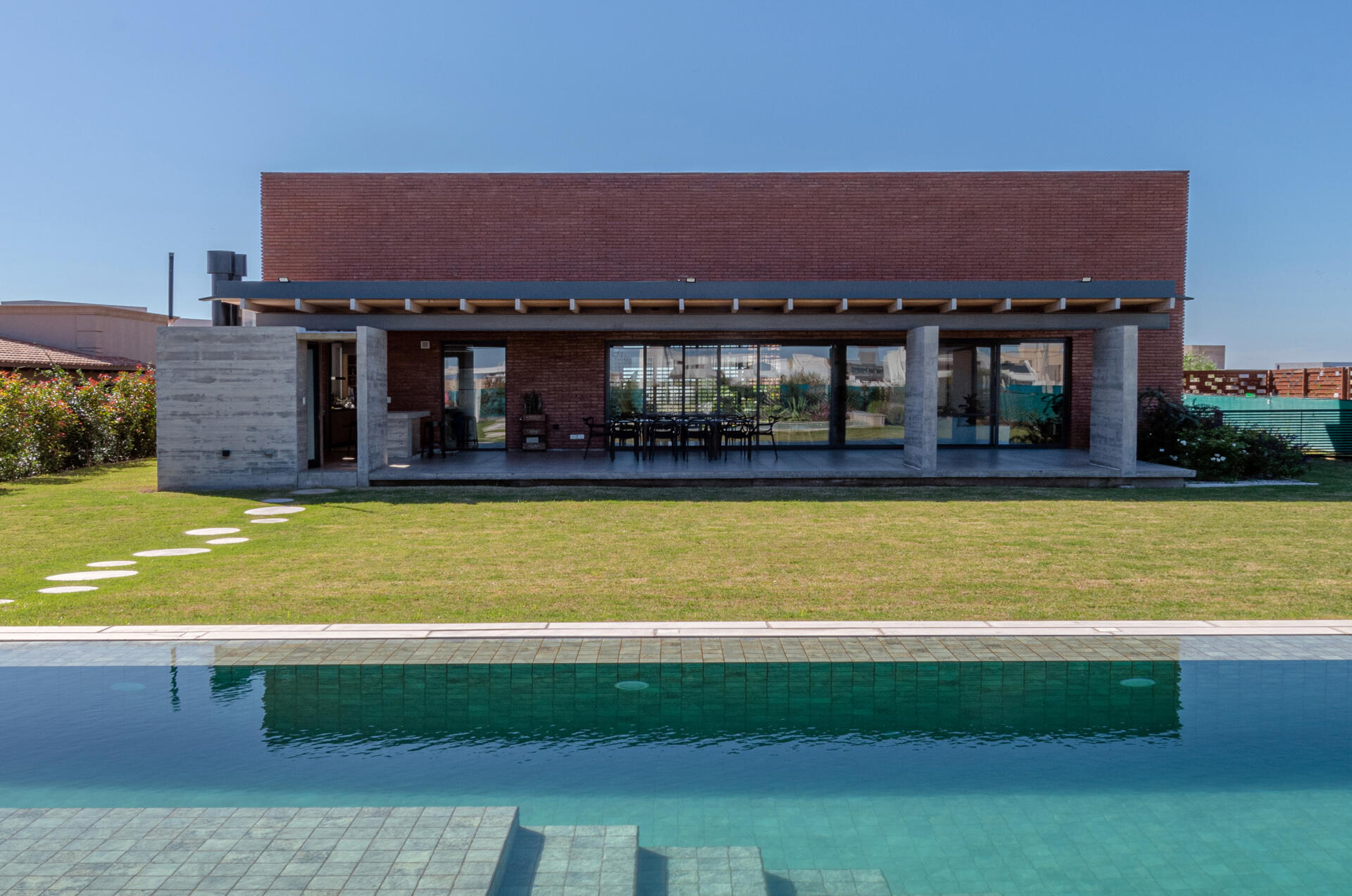 At the rear of the house, the home opens up to a covered terrace with an outdoor kitchen, as well a lawn area and swimming pool.
