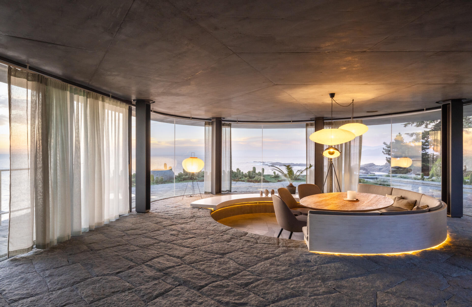 A curved dining space with built-in a banquette is designed to stay visually connected to the sea from every angle.