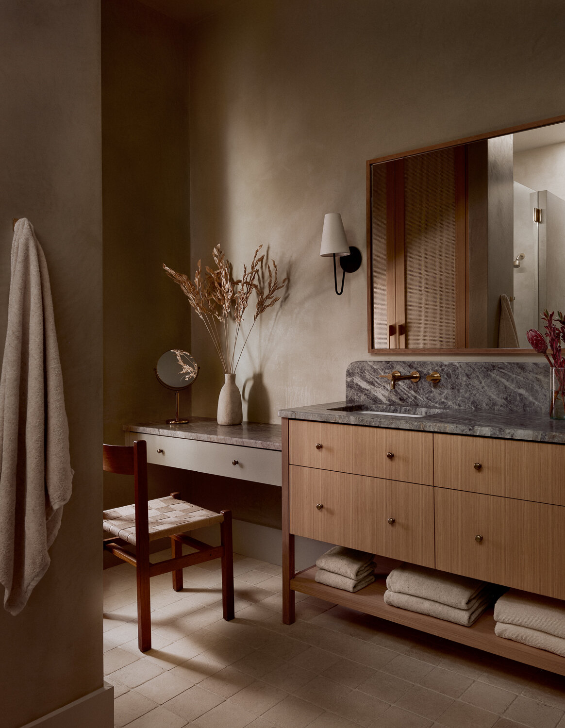 The primary bathroom introduces a dramatic natural material palette. Leathered quartzite is used for the countertops, tub deck, and tub face, while locally sourced white limestone tile covers the floors, creating balance through texture and tone.