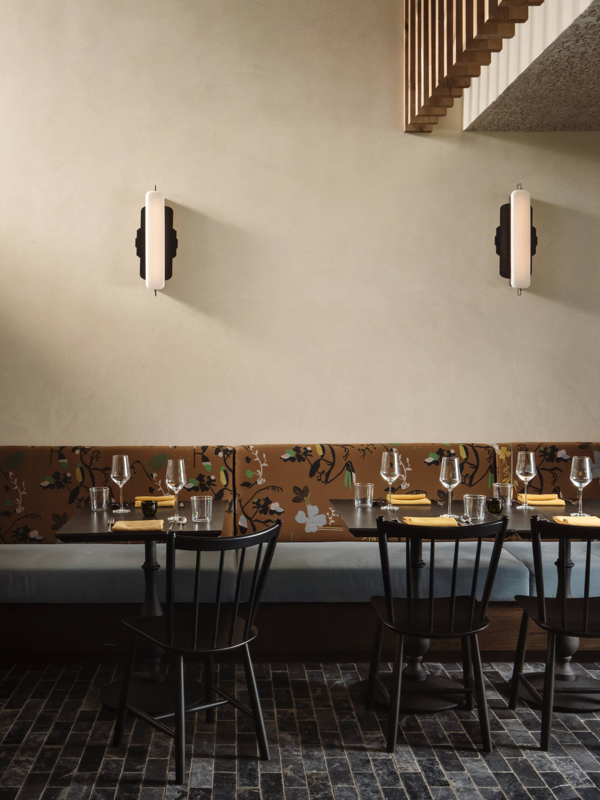 Dining and bar areas flow from this same palette, mixing plaster walls, patterned banquettes, dark wood tables, and a softly lit bar finished in stone, tile, and timber. Together, the spaces feel cohesive, relaxed, and designed for unhurried moments rather than quick arrivals.