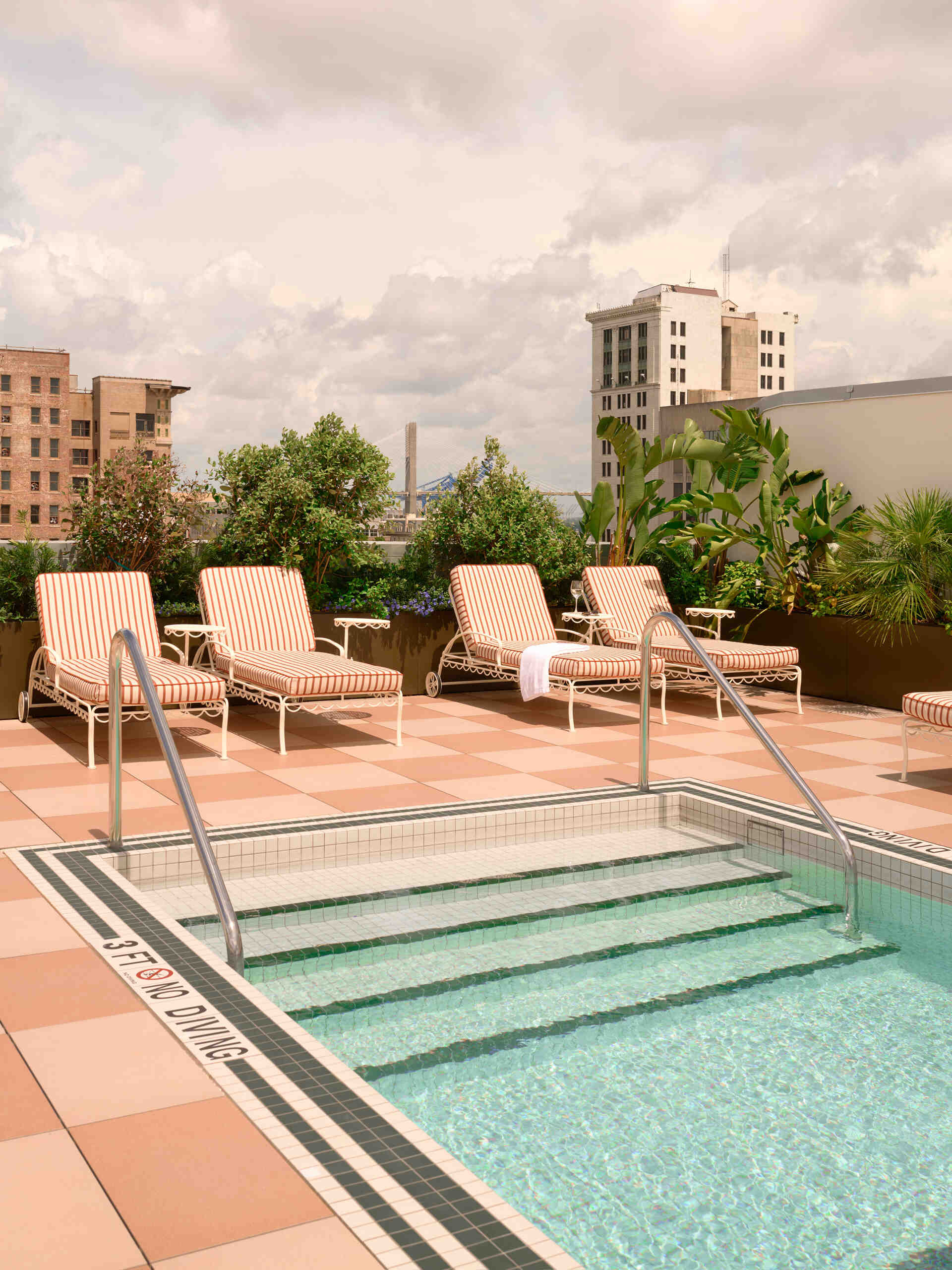 An open air rooftop features a compact bar, terraced seating, and a pool with views across Savannah’s parks and church spires.
