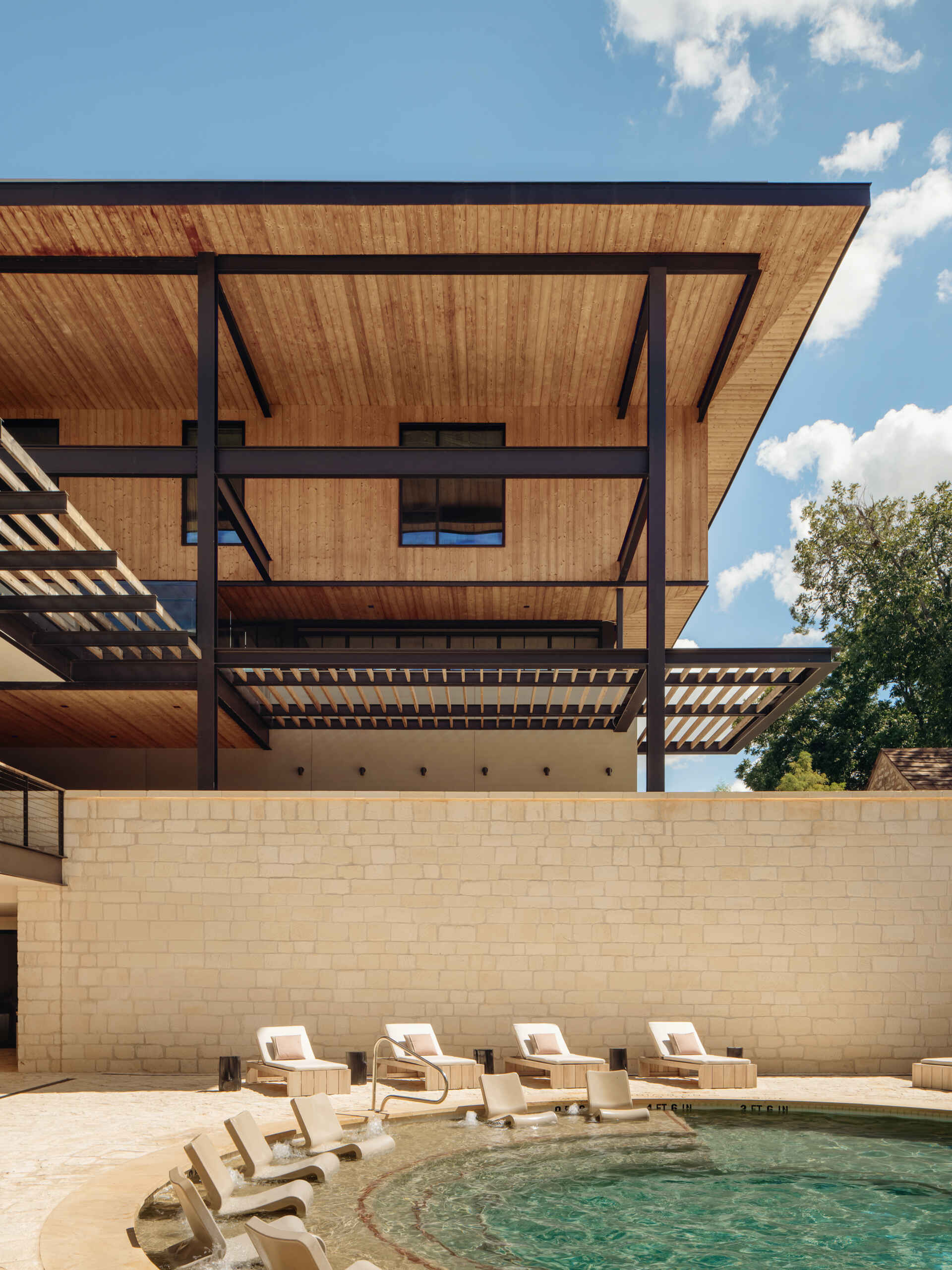 A sunken outdoor limestone pool anchors the outdoor amenities. Paired with a lounge area, it offers a sheltered place to step away from the heat while remaining within the landscape of the property.
