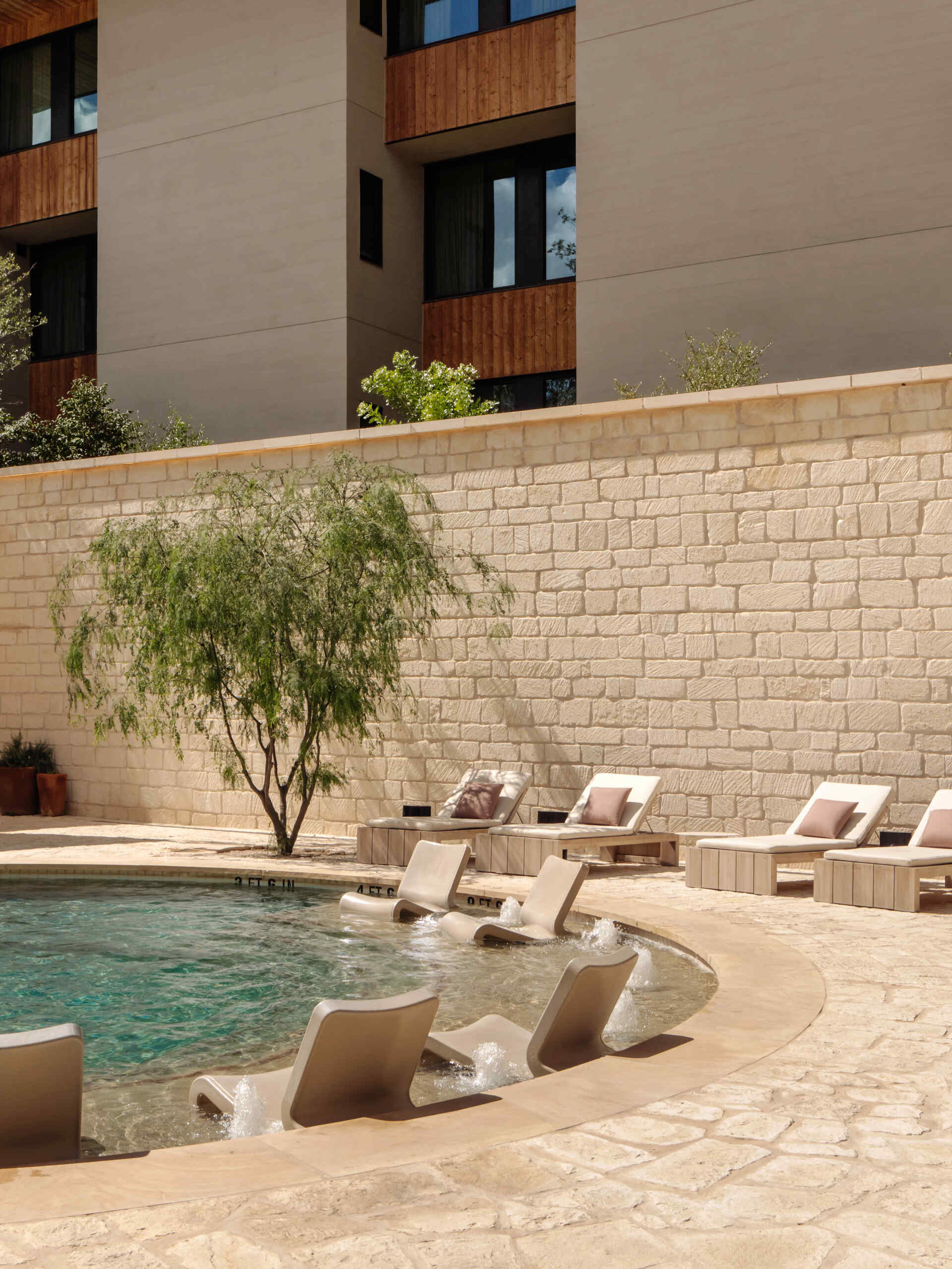 A sunken outdoor limestone pool anchors the outdoor amenities. Paired with a lounge area, it offers a sheltered place to step away from the heat while remaining within the landscape of the property.