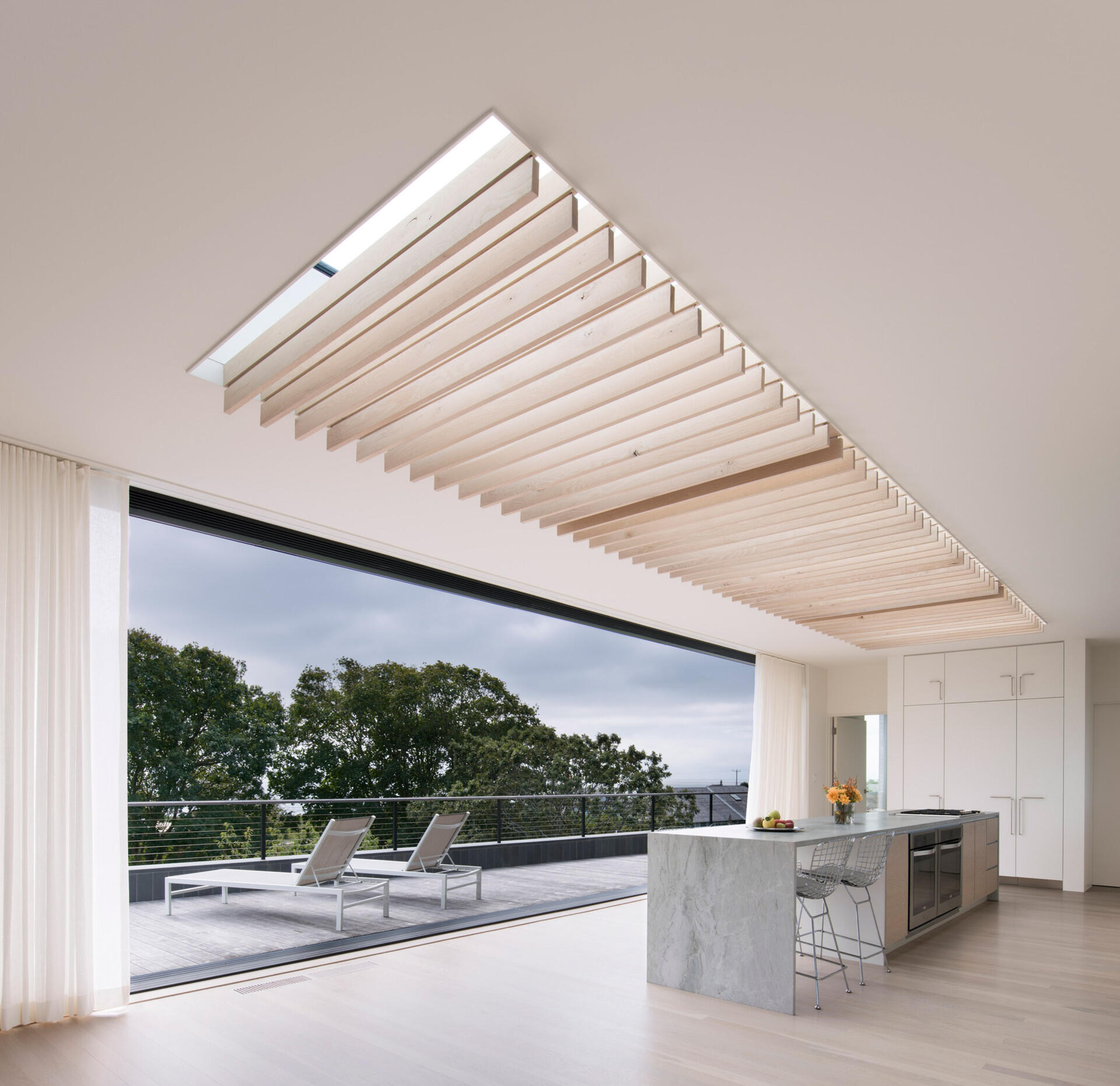 Las contraventanas de roble bajo el tragaluz de gran tamaño se mecen con la brisa del mar, proyectando luces y sombras en constante cambio, aportando movimiento y calma al interior.